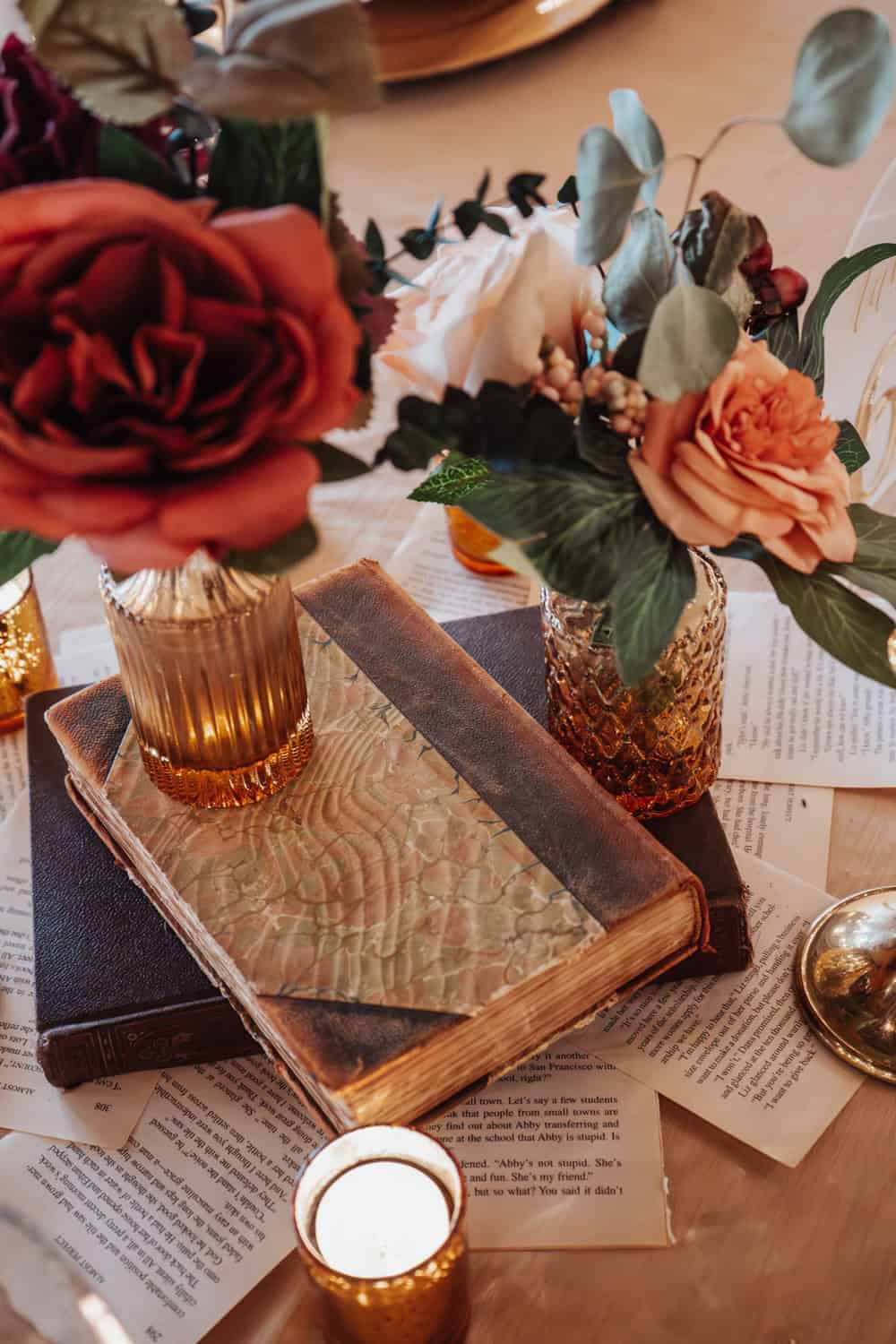 Beautiful floral arrangement with roses and eucalyptus in gold vases on a wooden table.