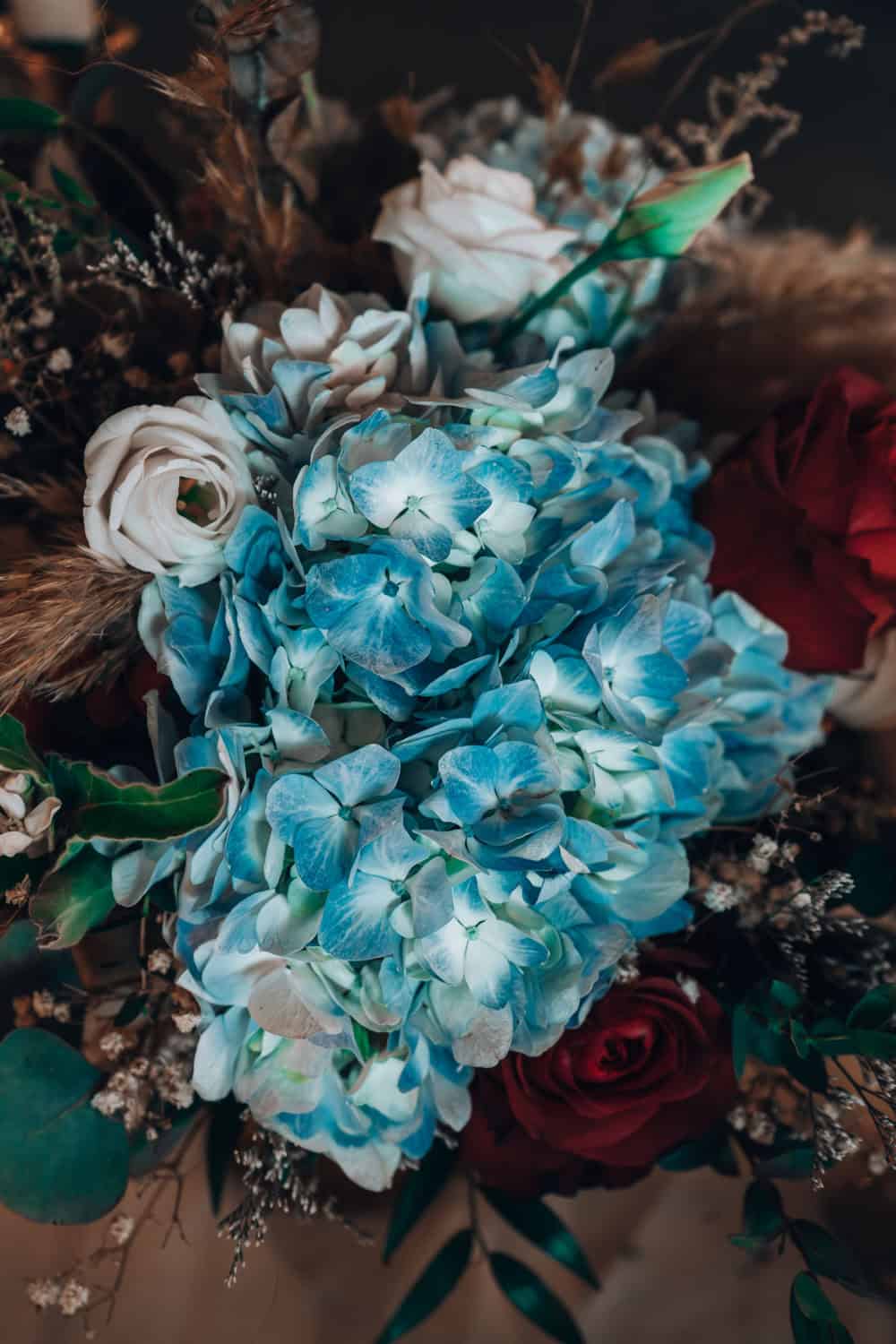 Beautiful blue hydrangeas with roses and greenery in a floral bouquet.
