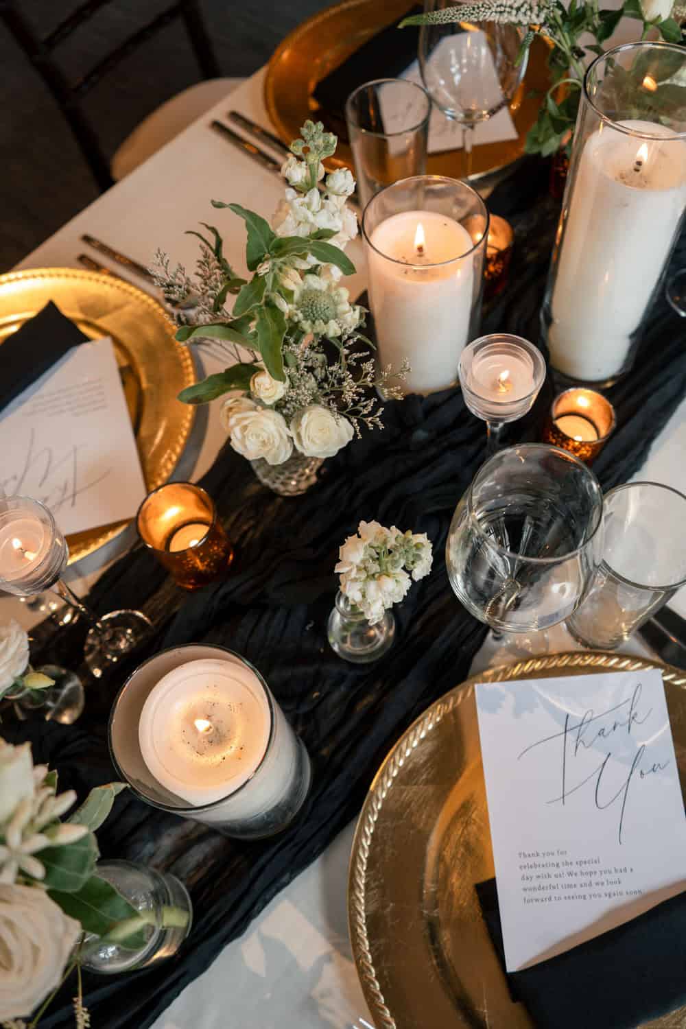 Elegant table setting with candles, flowers, and gold accents for a celebration.