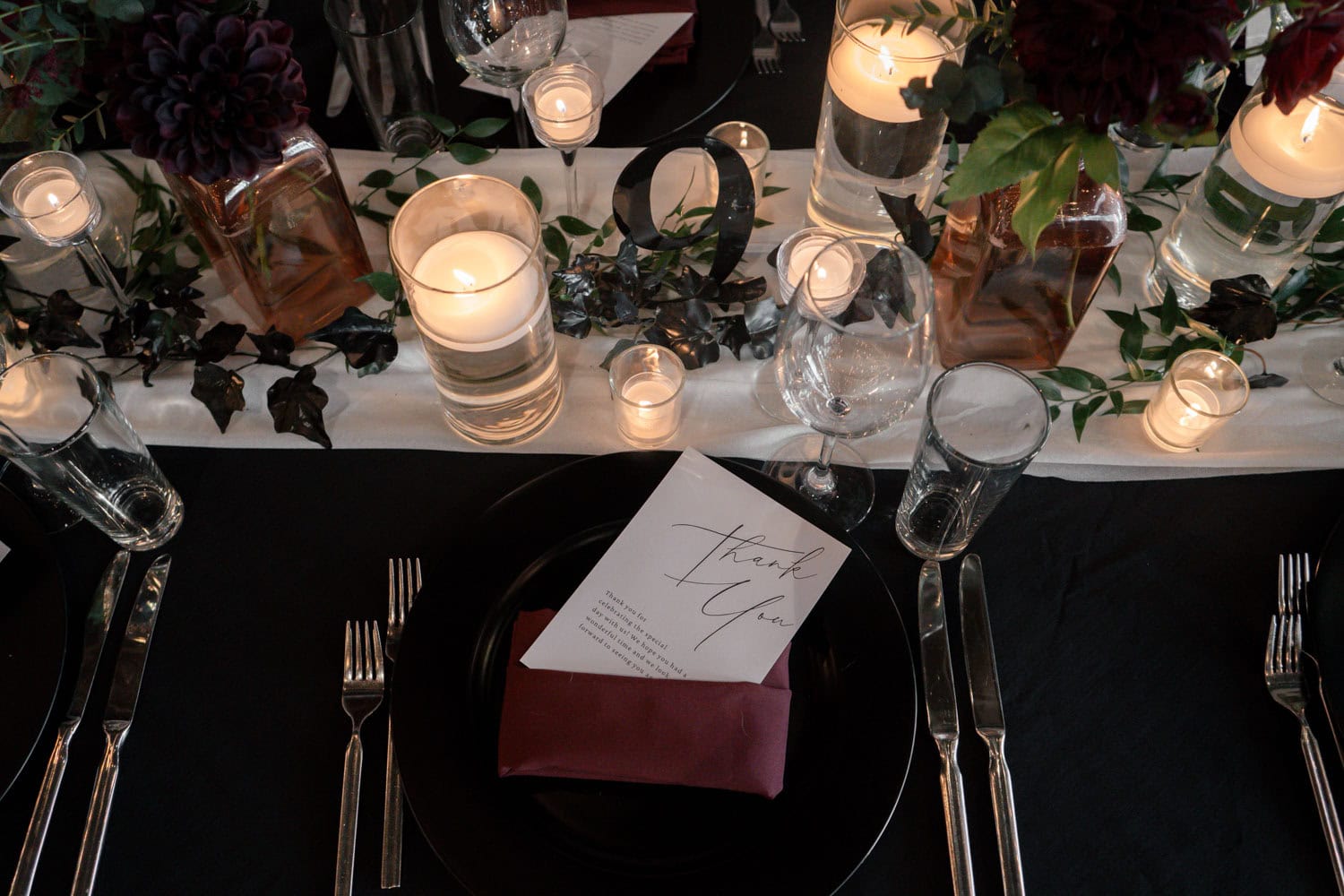 Elegant table setting with candles, flowers, and place card for special event.