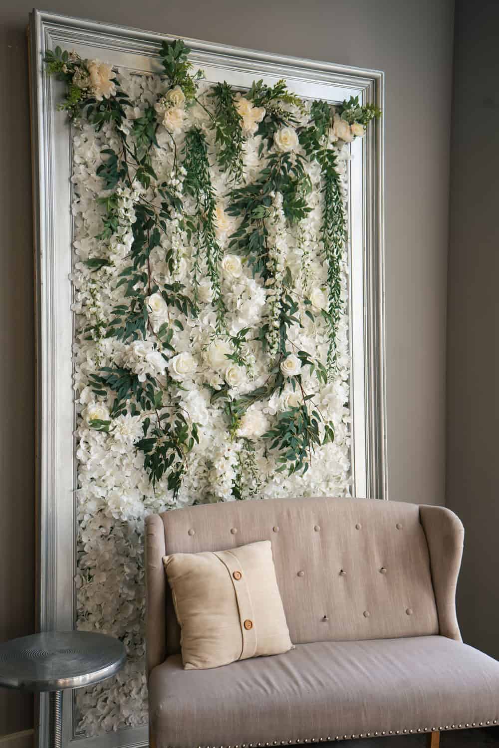 Beautiful floral wall backdrop with white flowers and greenery for wedding decor.