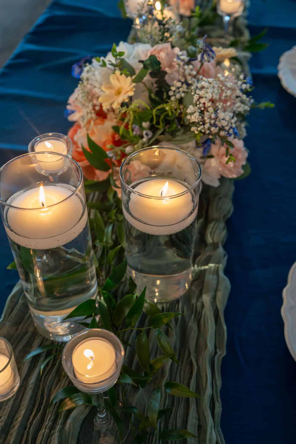 Wedding table centerpiece with candles and floral arrangement.