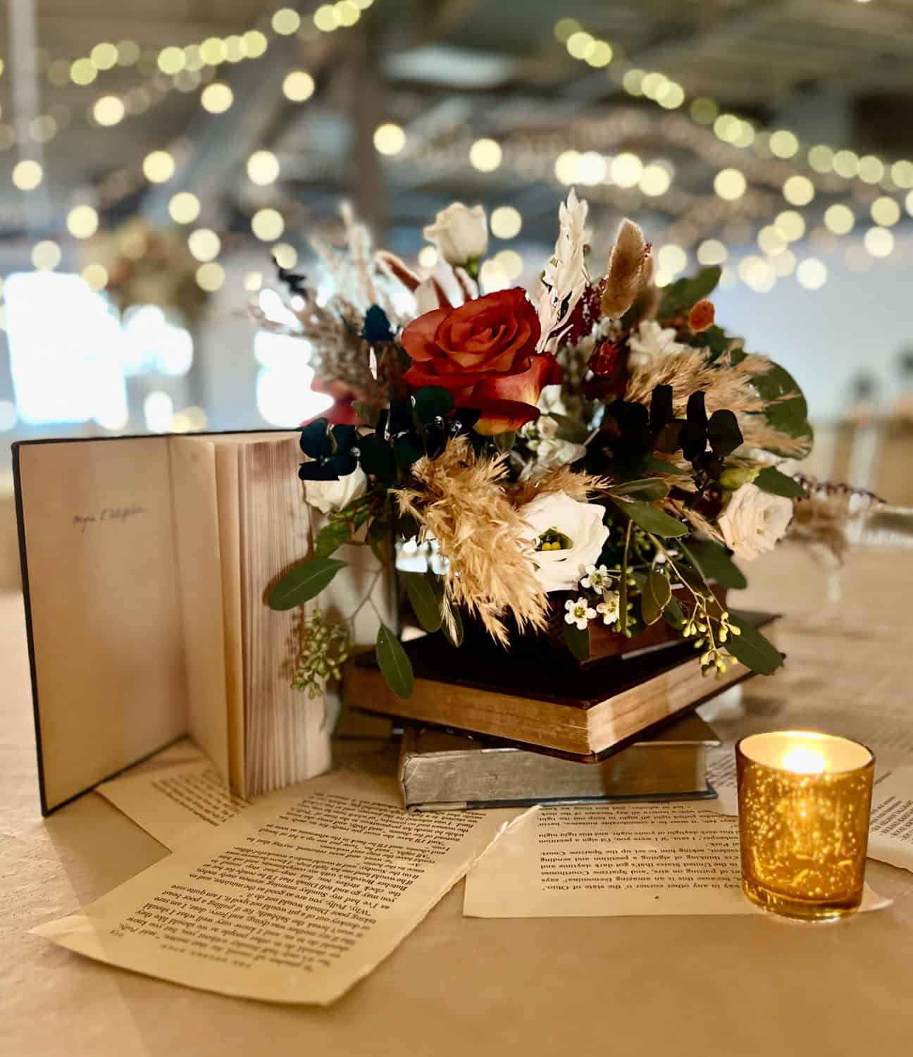 Beautiful floral centerpiece with candles and open books for cozy ambiance.