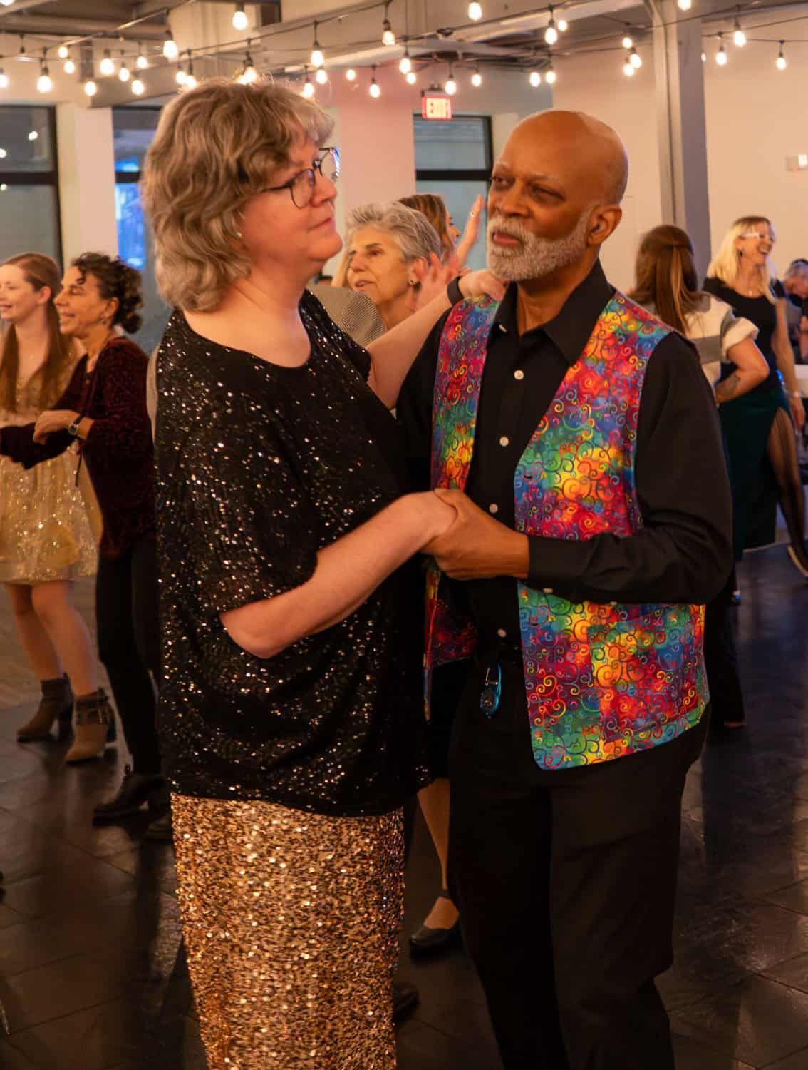 Couple dancing at SKY Armory with festive lighting and guests in background.