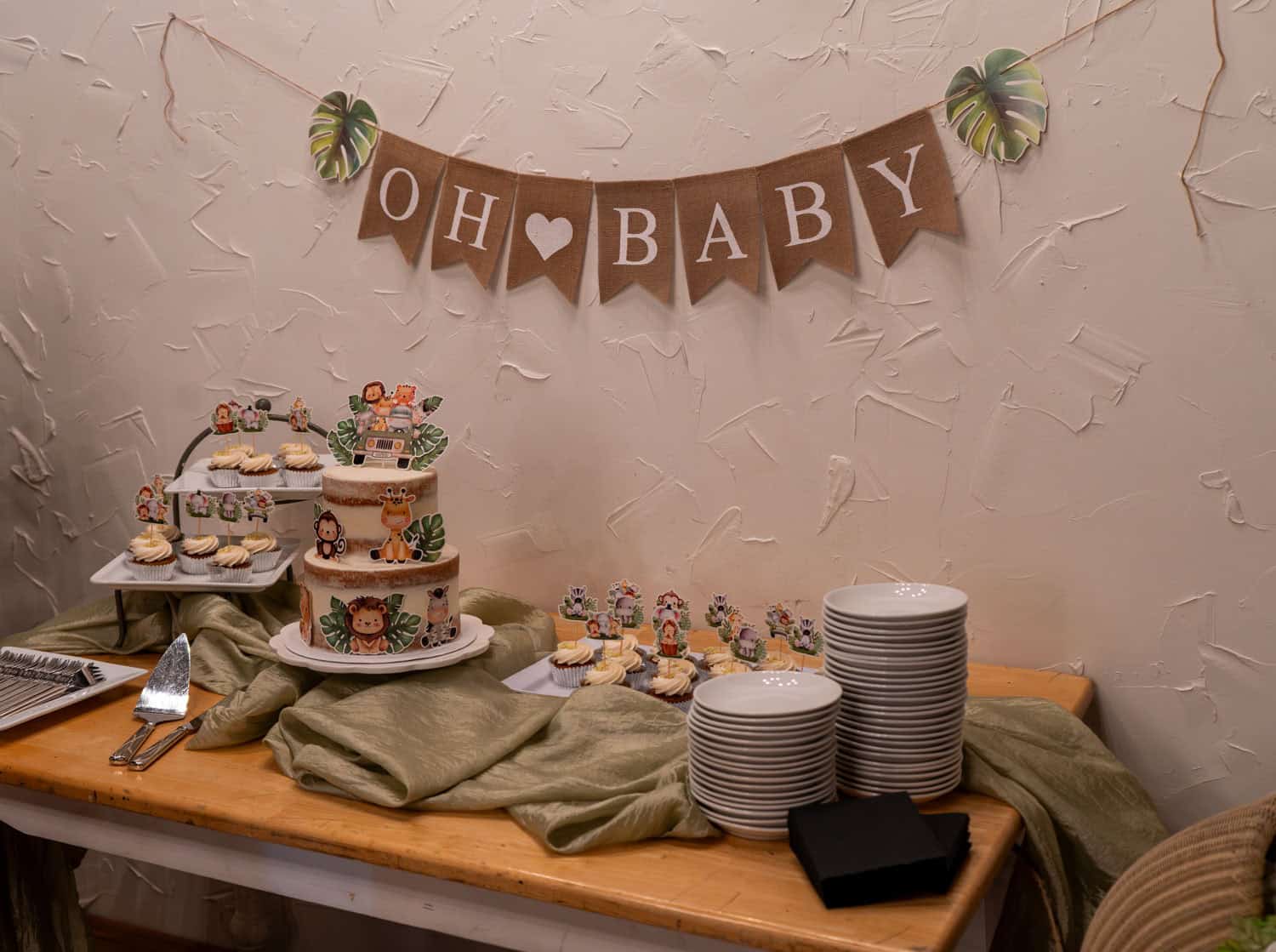 Decorative dessert table for baby shower with cupcakes and cake.