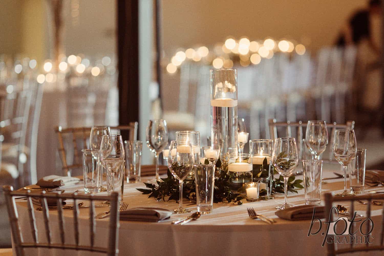 Decorated event table with candles, glassware, and floral centerpiece for wedding reception.