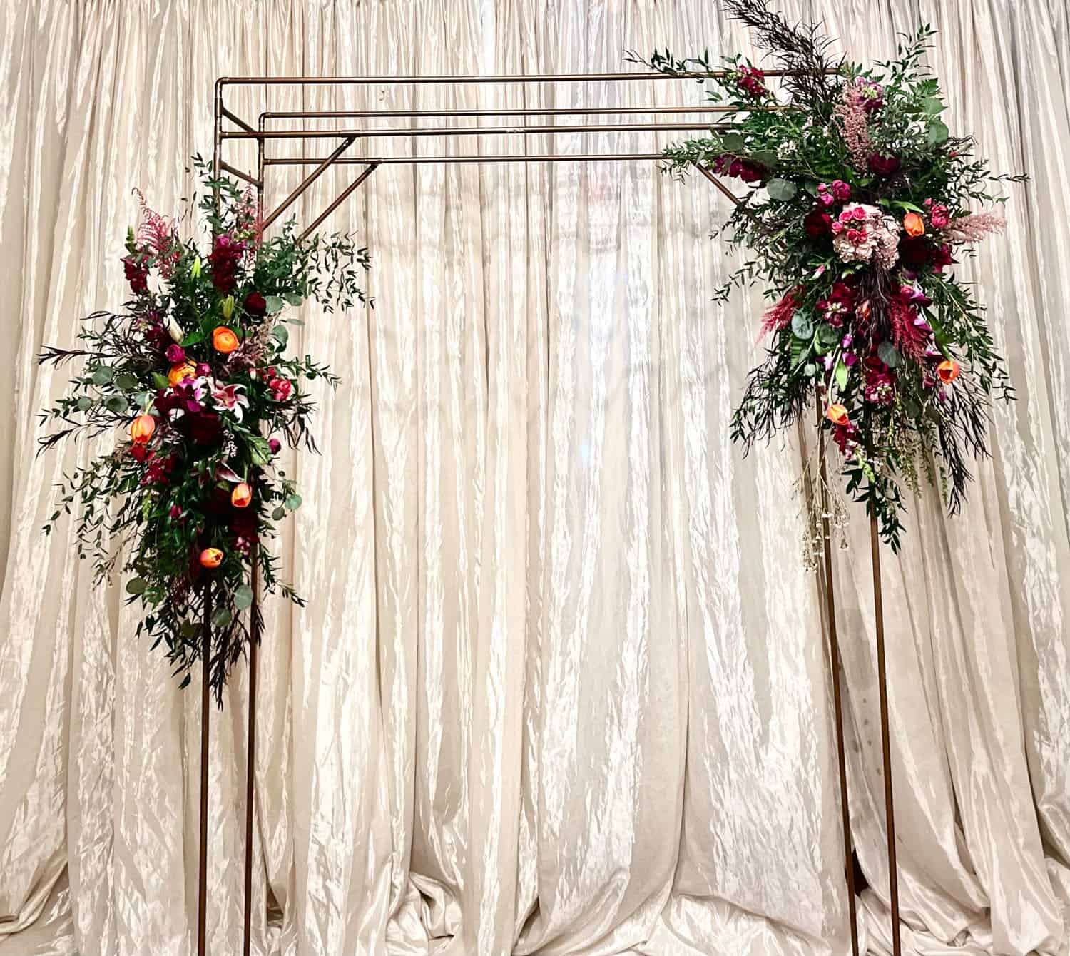 Beautiful floral wedding arch with pink, red, and orange flowers at SKY Armory.