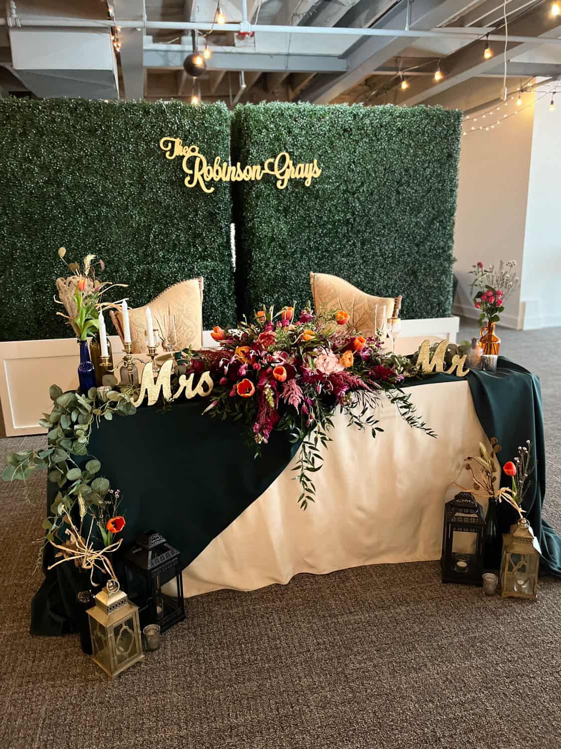 Wedding reception table with floral arrangements and personalized signs at SKY Armory.
