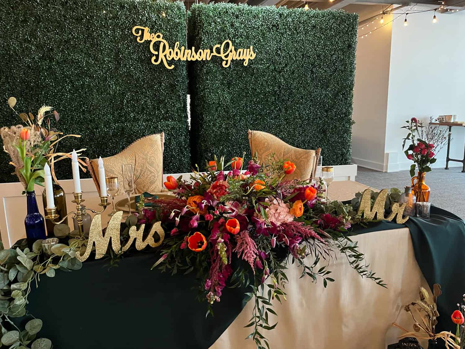 Wedding reception table with floral centerpiece and 'Mrs & Mr' signs.