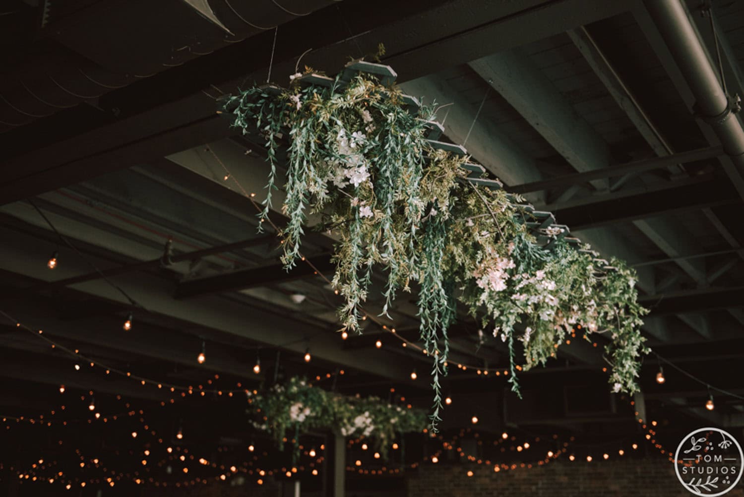 Wedding decoration with hanging greenery and string lights for elegant ambiance.