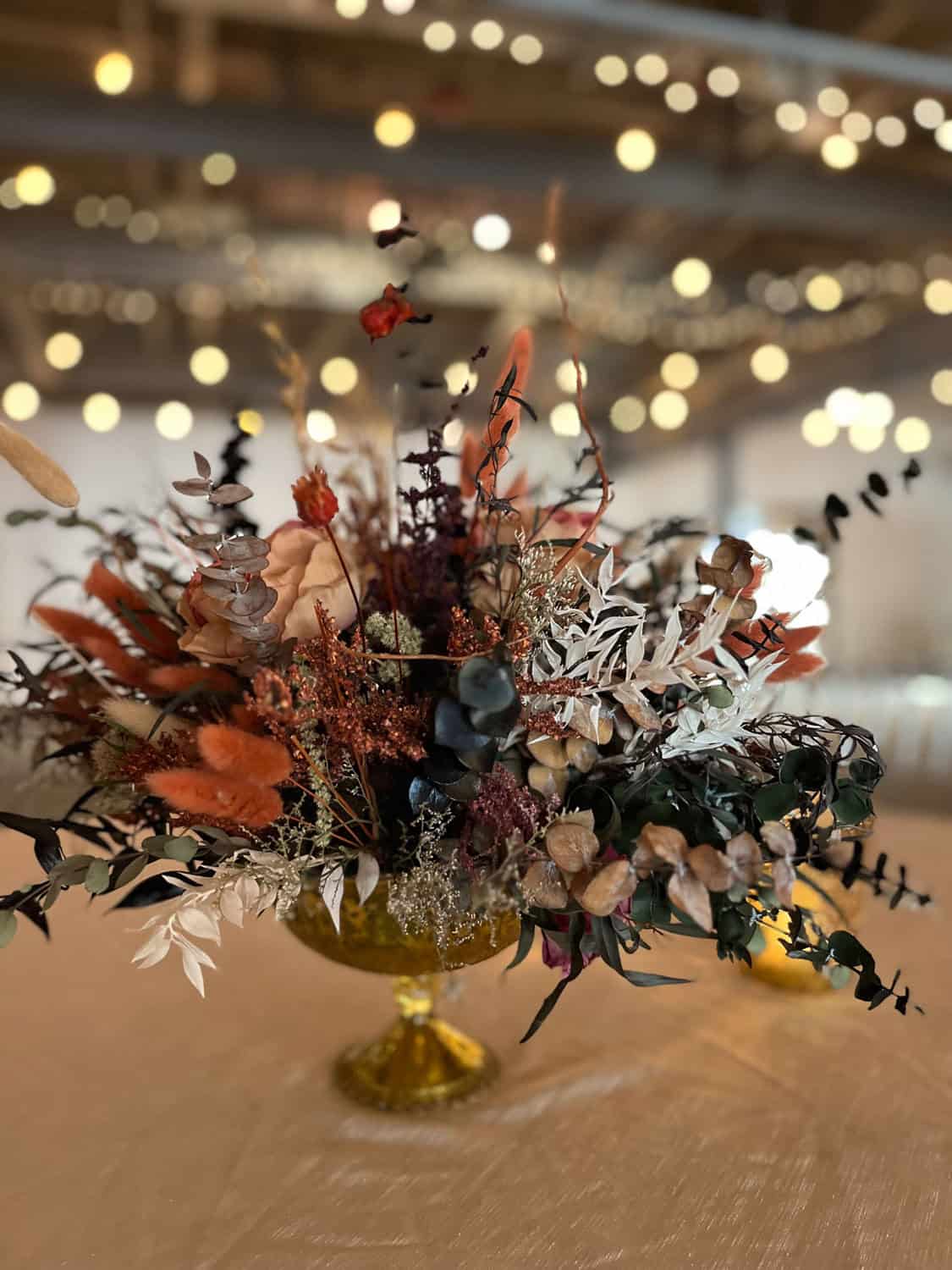 Beautiful dried flower bouquet in a gold vase with warm lighting.