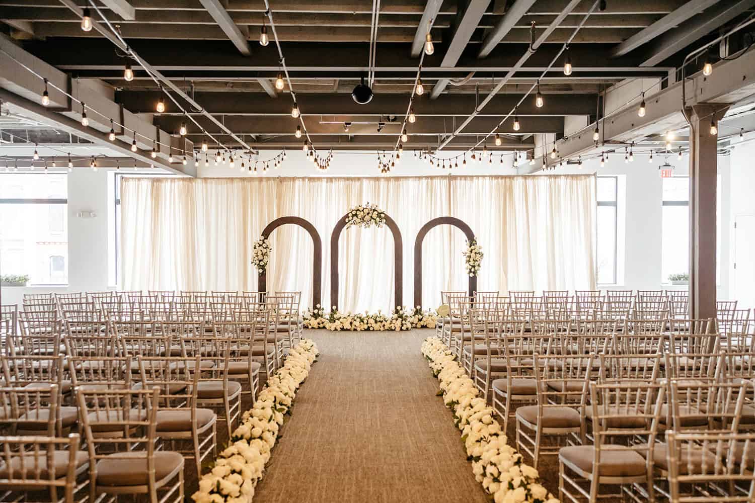 Wedding ceremony setup with floral arches and rows of chairs at SKY Armory.