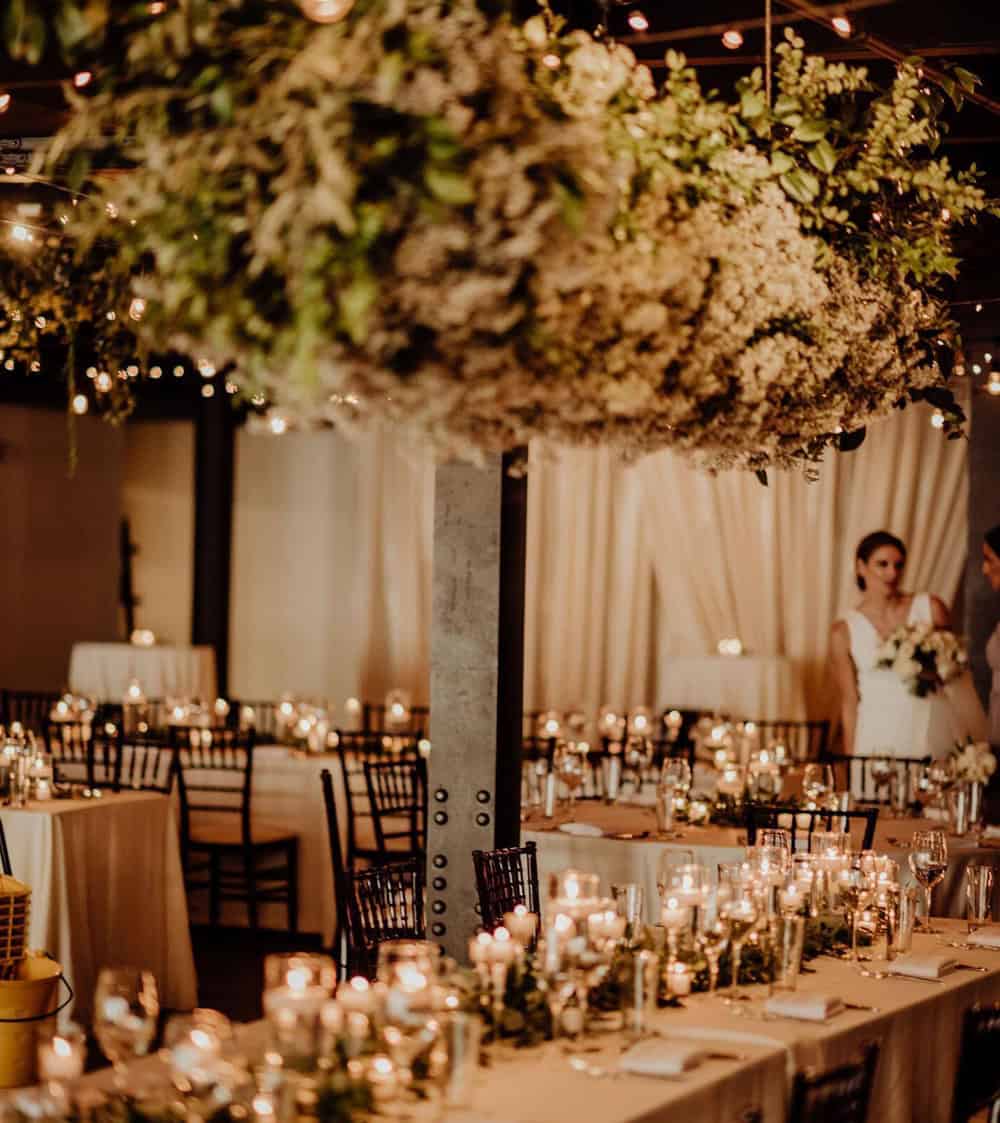 Beautifully decorated wedding reception with floral centerpieces and candlelit tables at SKY Armory.