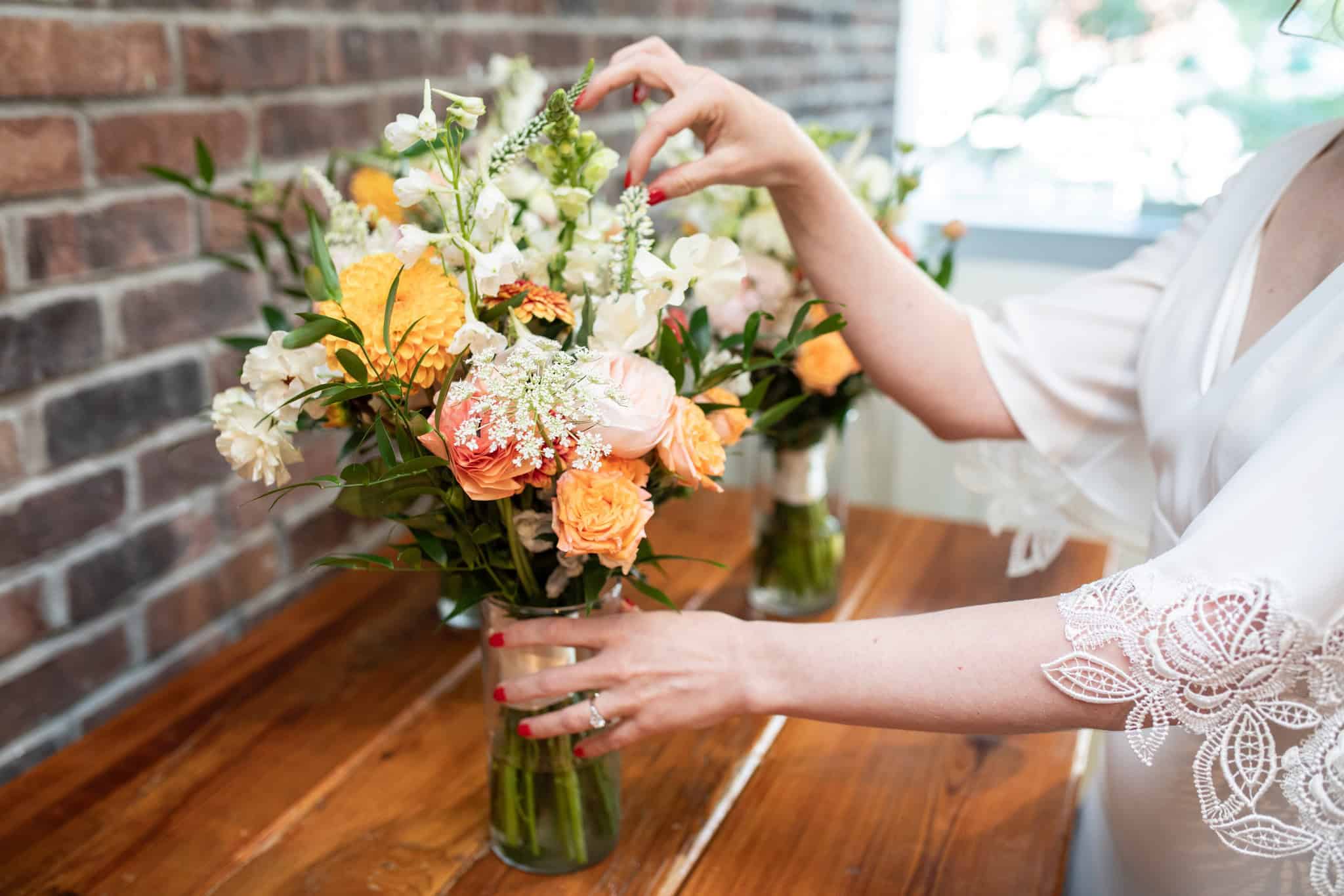 Person arranging a colorful flower bouquet in a glass vase at SKY Armory.