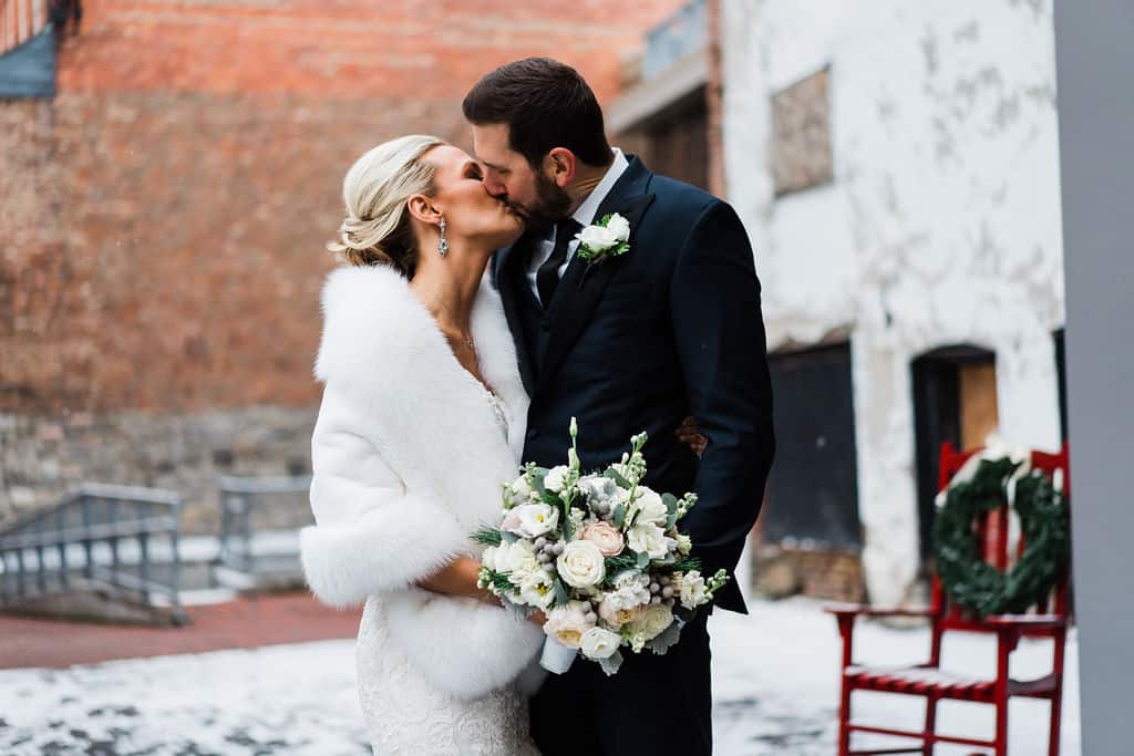 SKY Armory Wedding Couple Bride and groom sharing a kiss outdoors in winter.