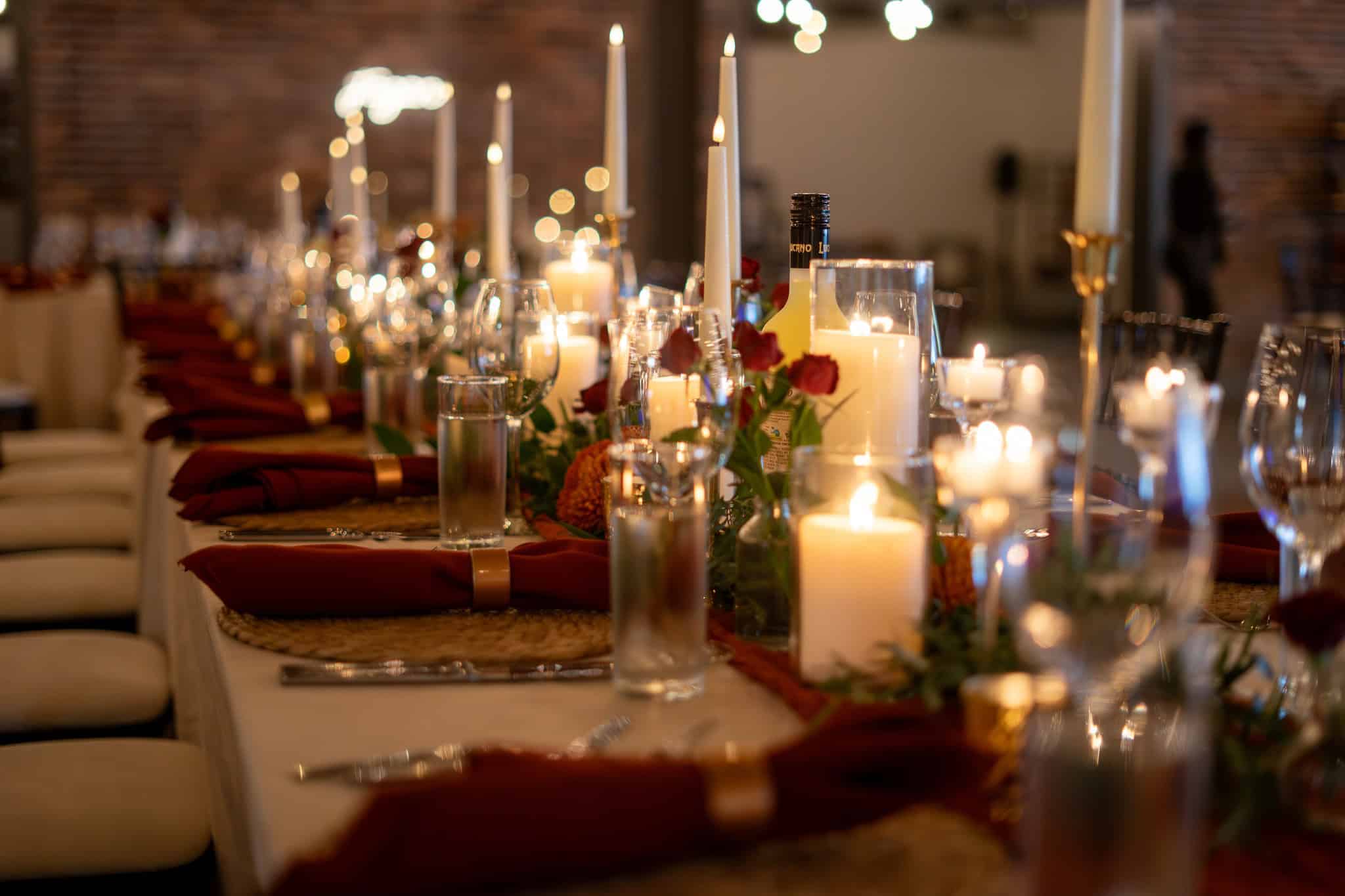 Decorated wedding reception table with candles and floral arrangements.