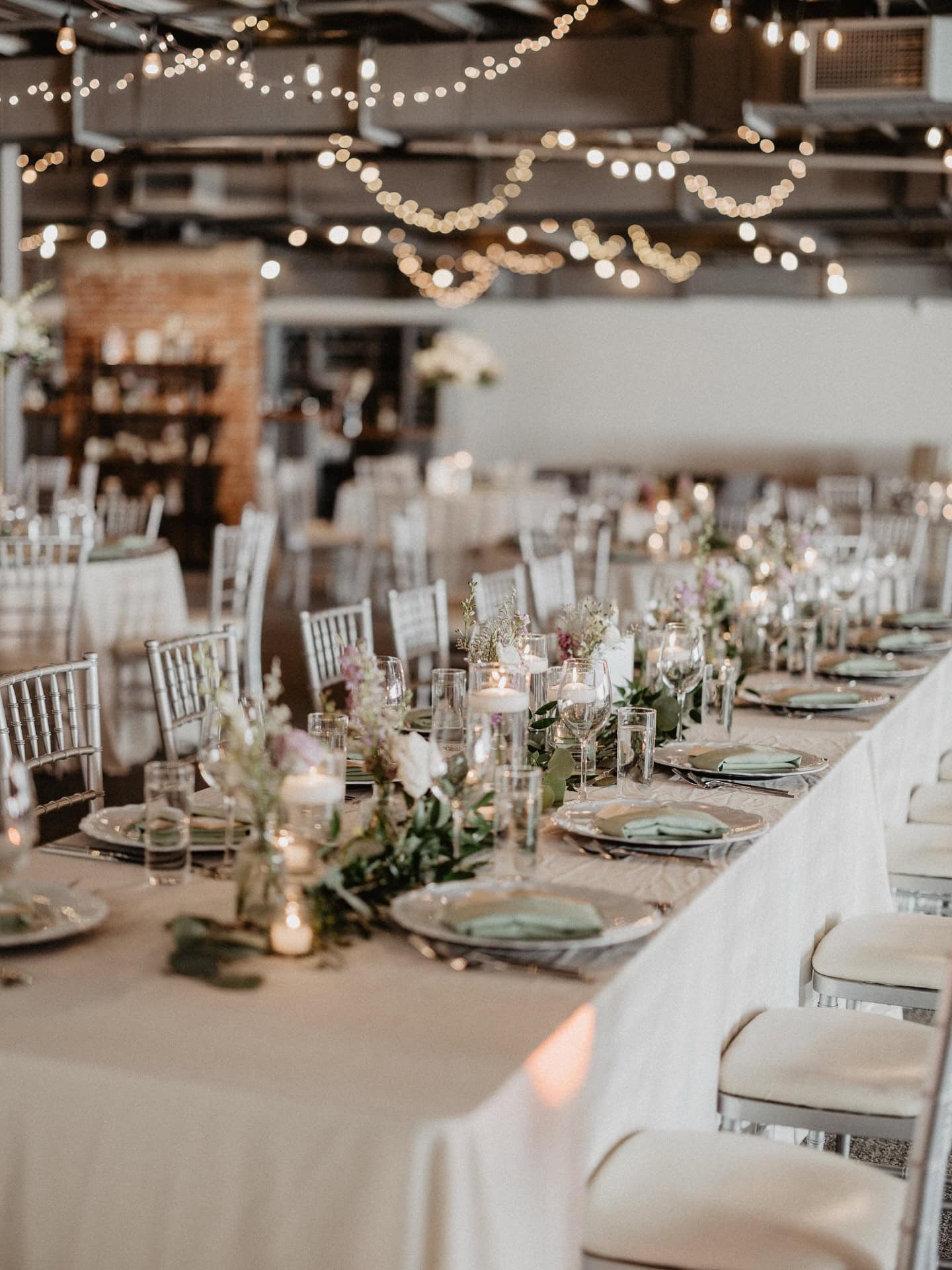 Beautifully decorated wedding reception with string lights and floral centerpieces.