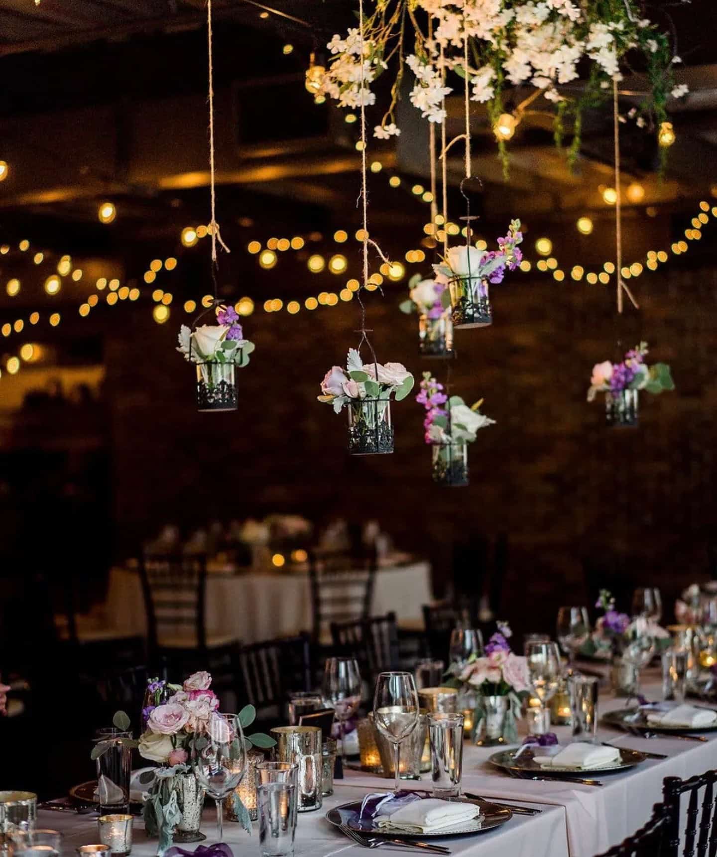 Beautiful wedding reception with hanging floral arrangements and string lights.