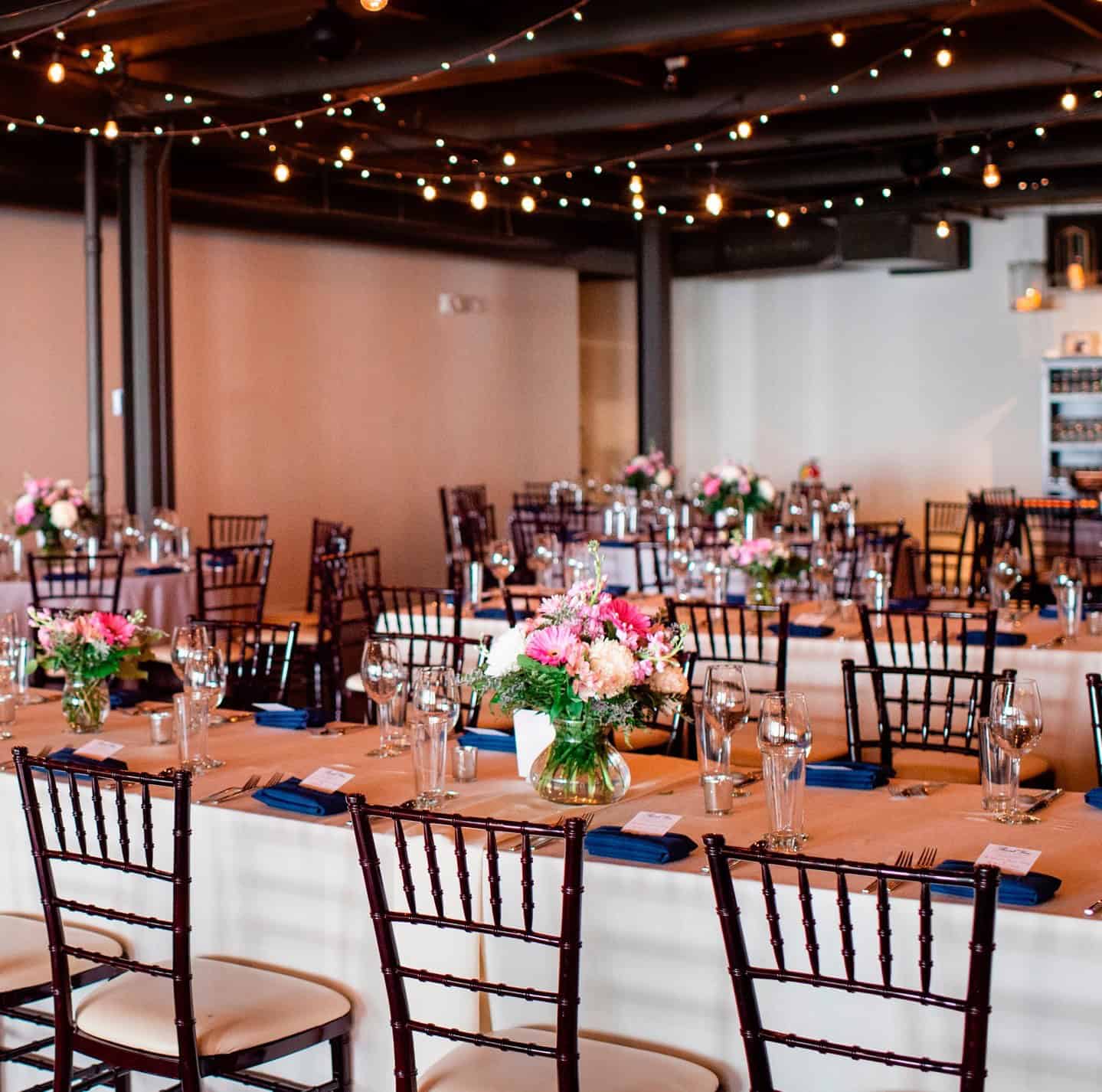 Beautifully decorated event space with floral centerpieces and string lights.