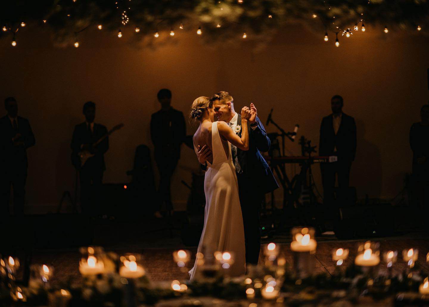 Couple dancing at wedding reception with live band in background.