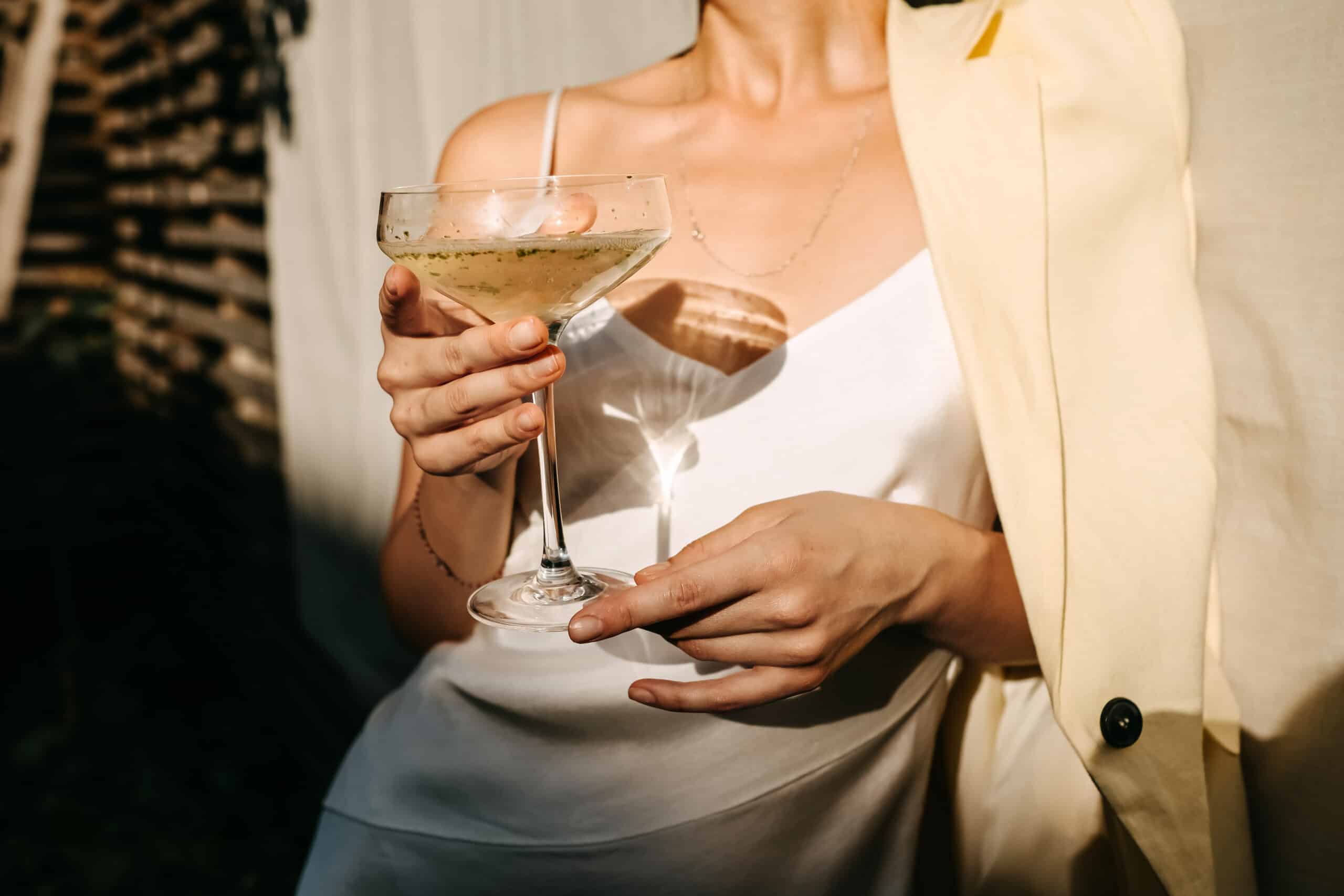 Woman holding a refreshing spring cocktail in a coupe glass.