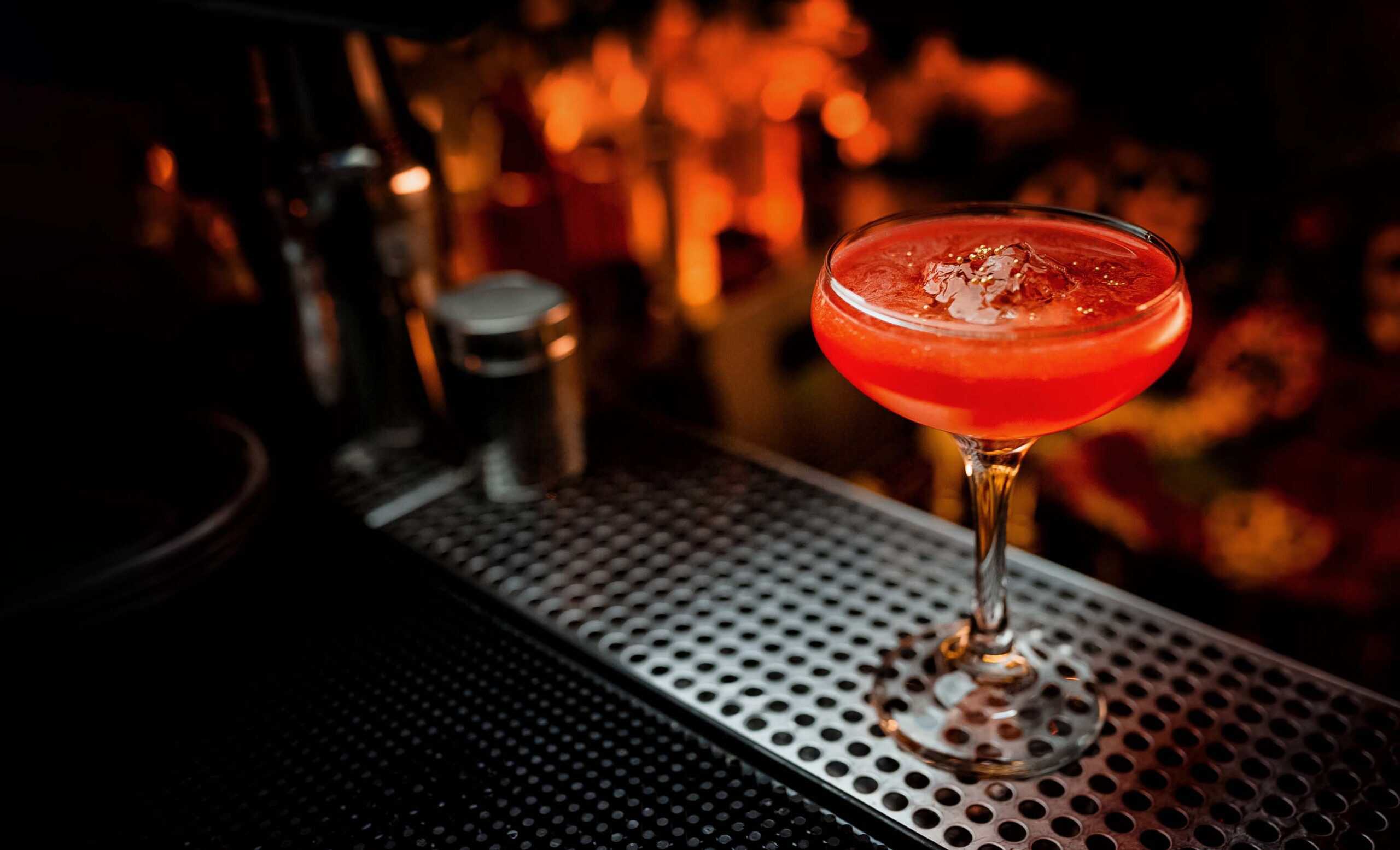 Red cocktail in a coupe glass on bar counter at SKY Armory.