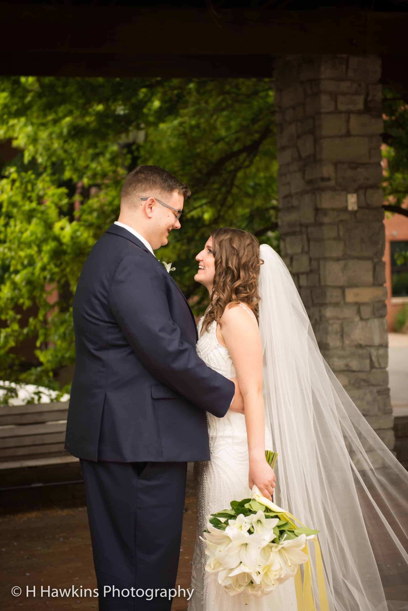 Bride and groom sharing a romantic moment outdoors with greenery background.