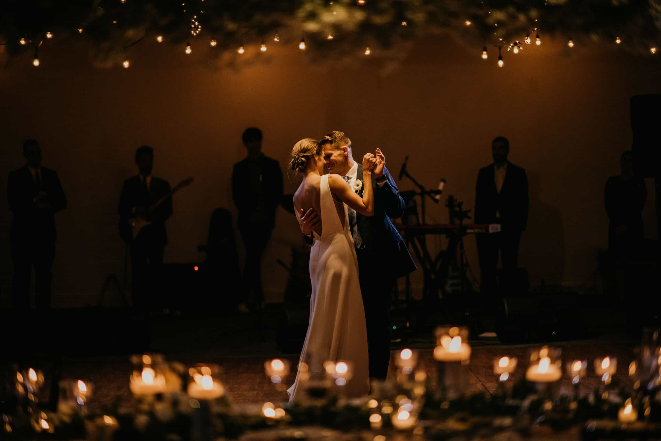 Couple dancing at wedding reception with live band in background.