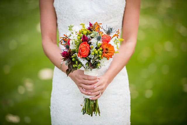 Bride holding a colorful wedding bouquet outdoors.