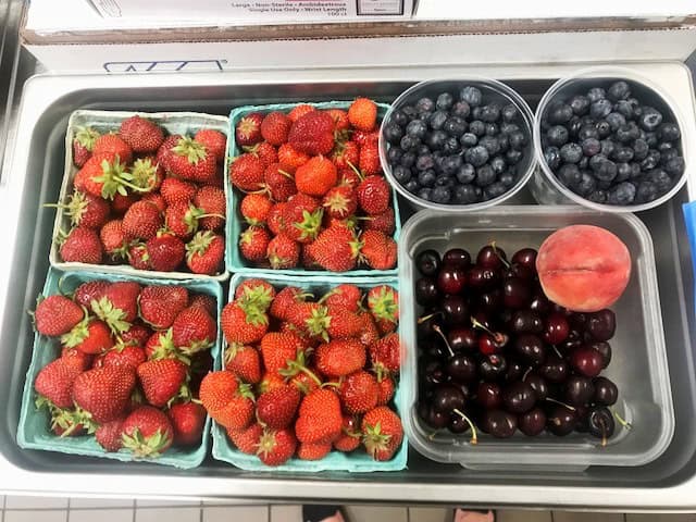 Assorted fresh berries including strawberries, blueberries, cherries, and a peach.