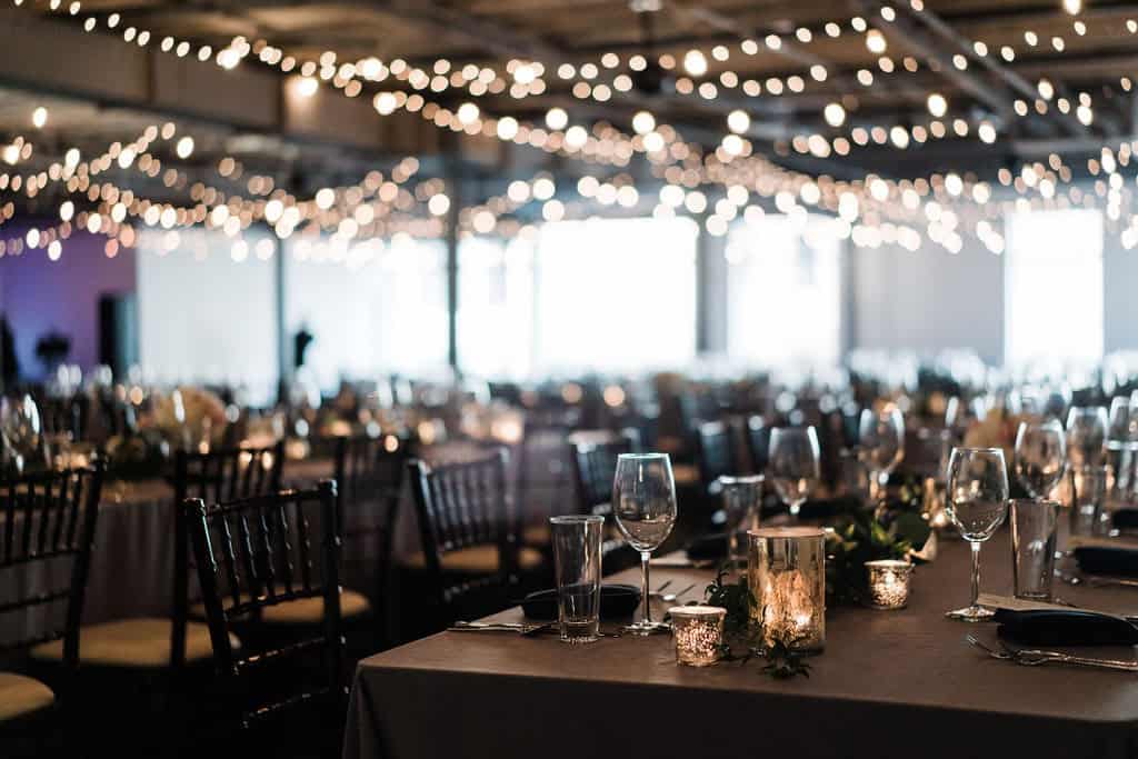 Interior of event venue with decorated tables and string lights for a celebration.