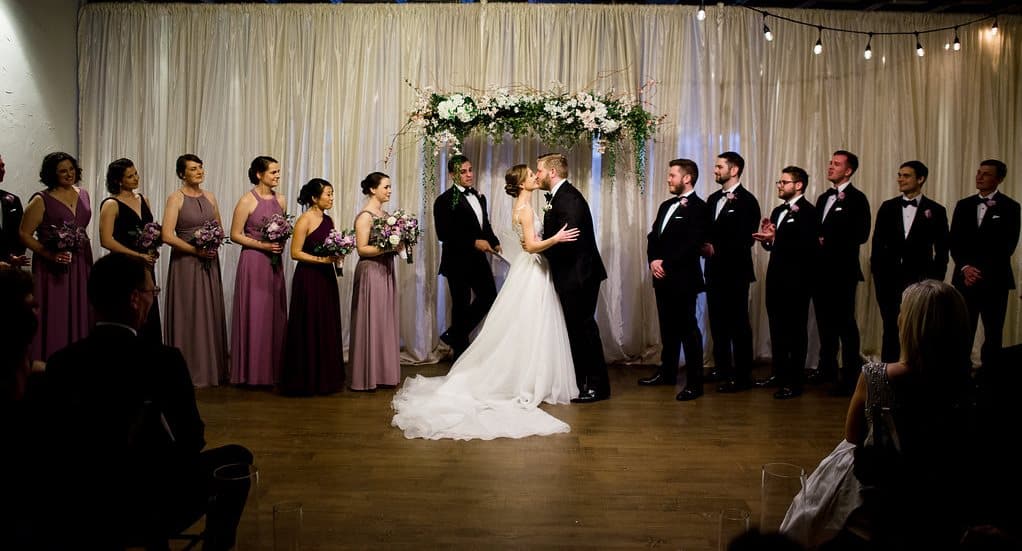 Bride and groom exchanging vows with wedding party at SKY Armory.