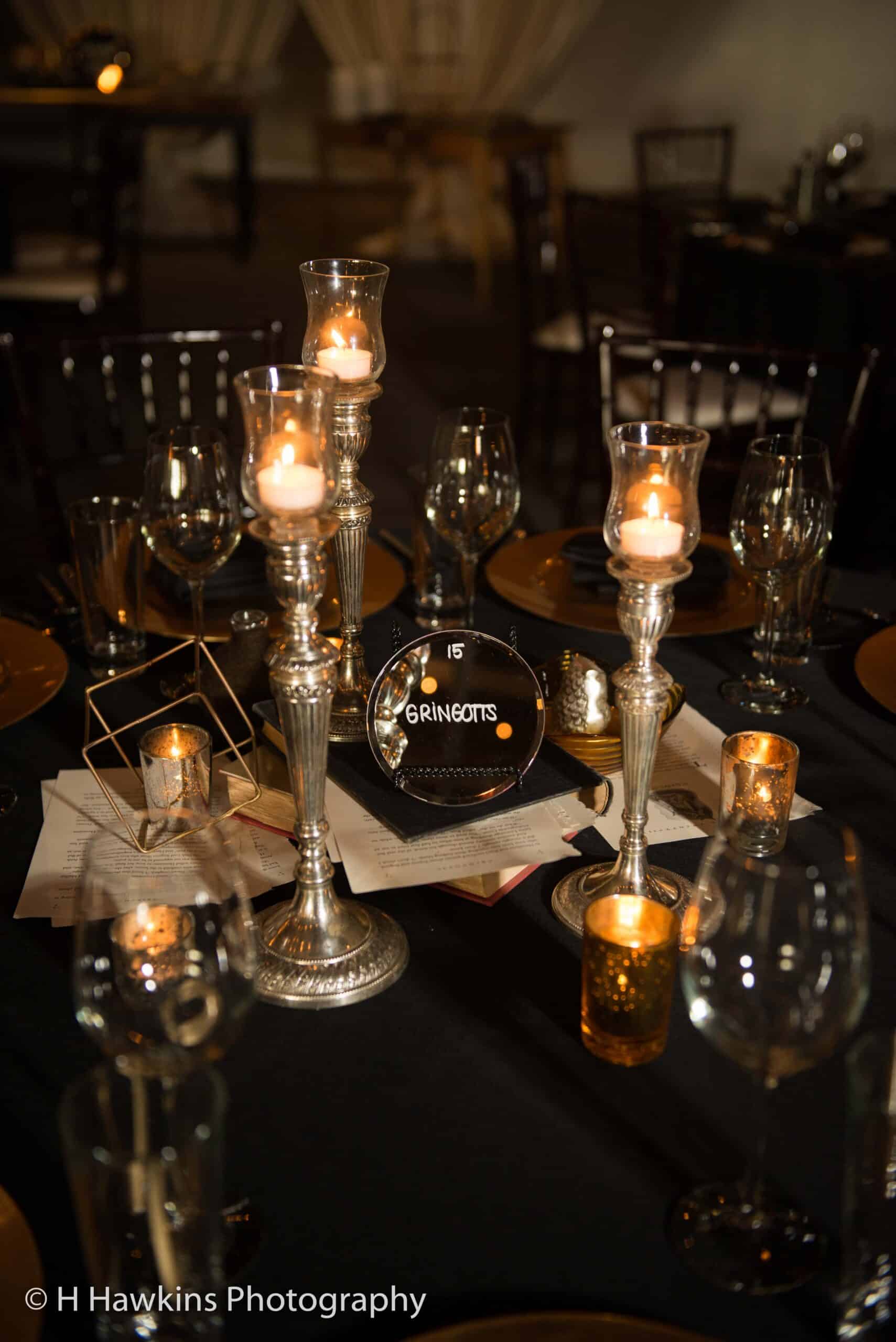 Elegant table setup with candles, glassware, and decorative centerpieces for event.