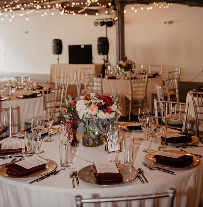 Wedding reception table with floral centerpiece and elegant tableware.