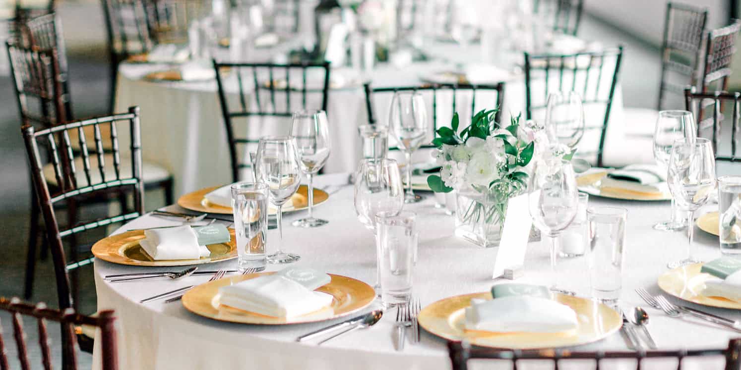 Beautifully arranged wedding reception table with white flowers and gold accents.