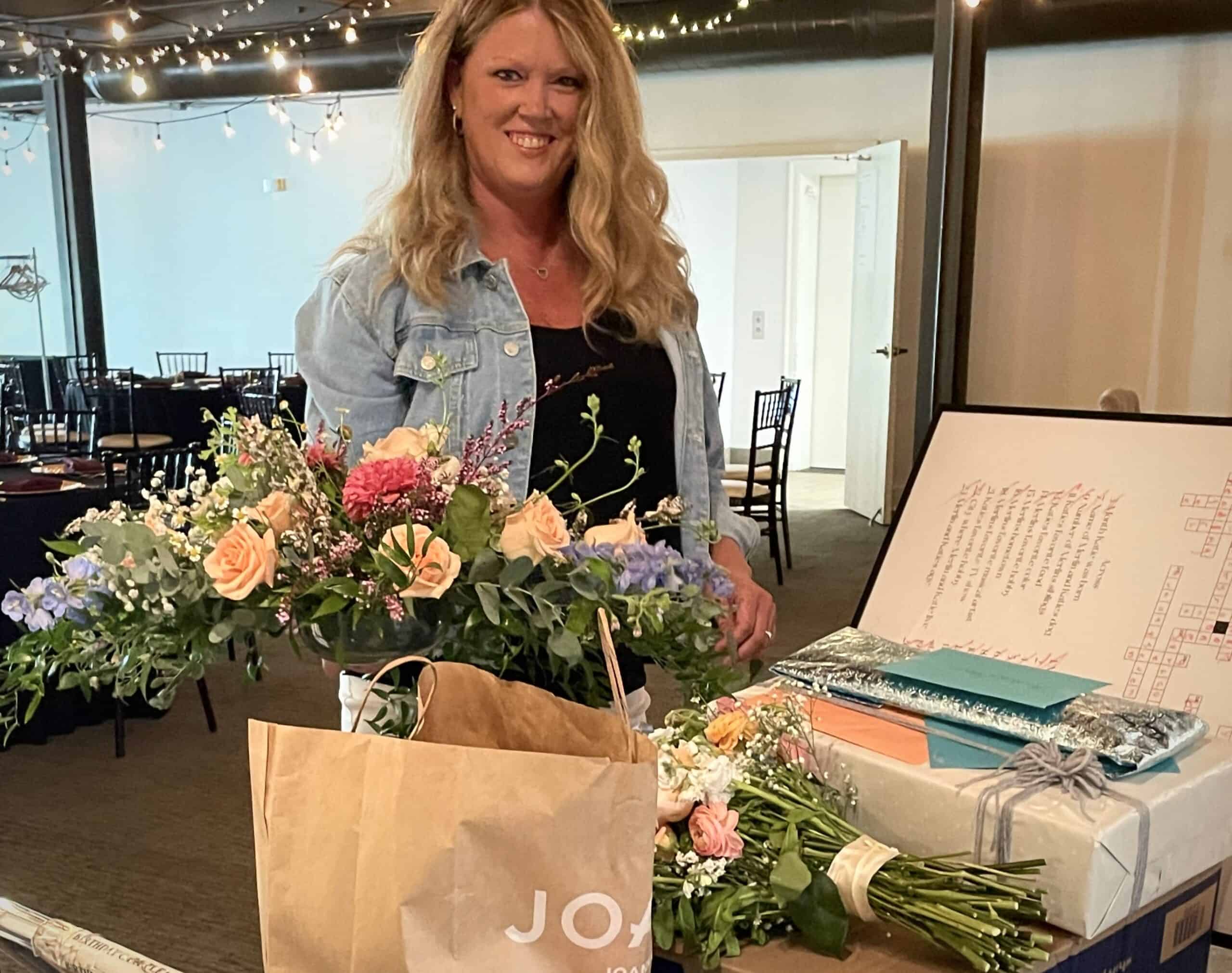 Woman smiling at SKY Armory with flowers and gifts.