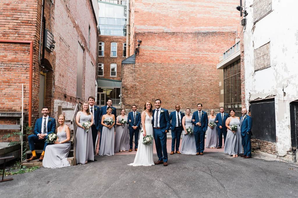 Wedding party with bride and groom in city alley with bridesmaids and groomsmen.