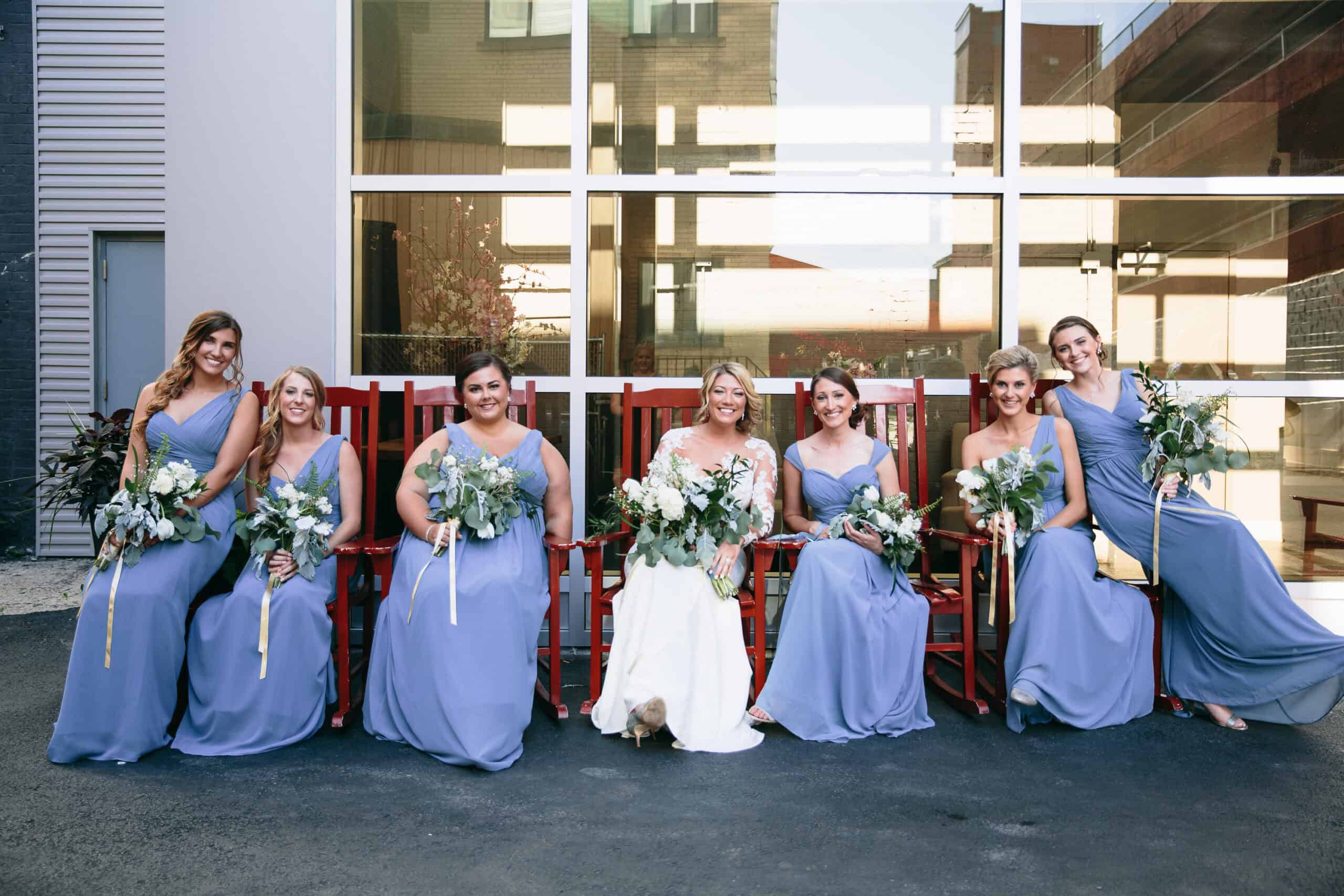 Bridal party with six women in blue dresses holding bouquets.