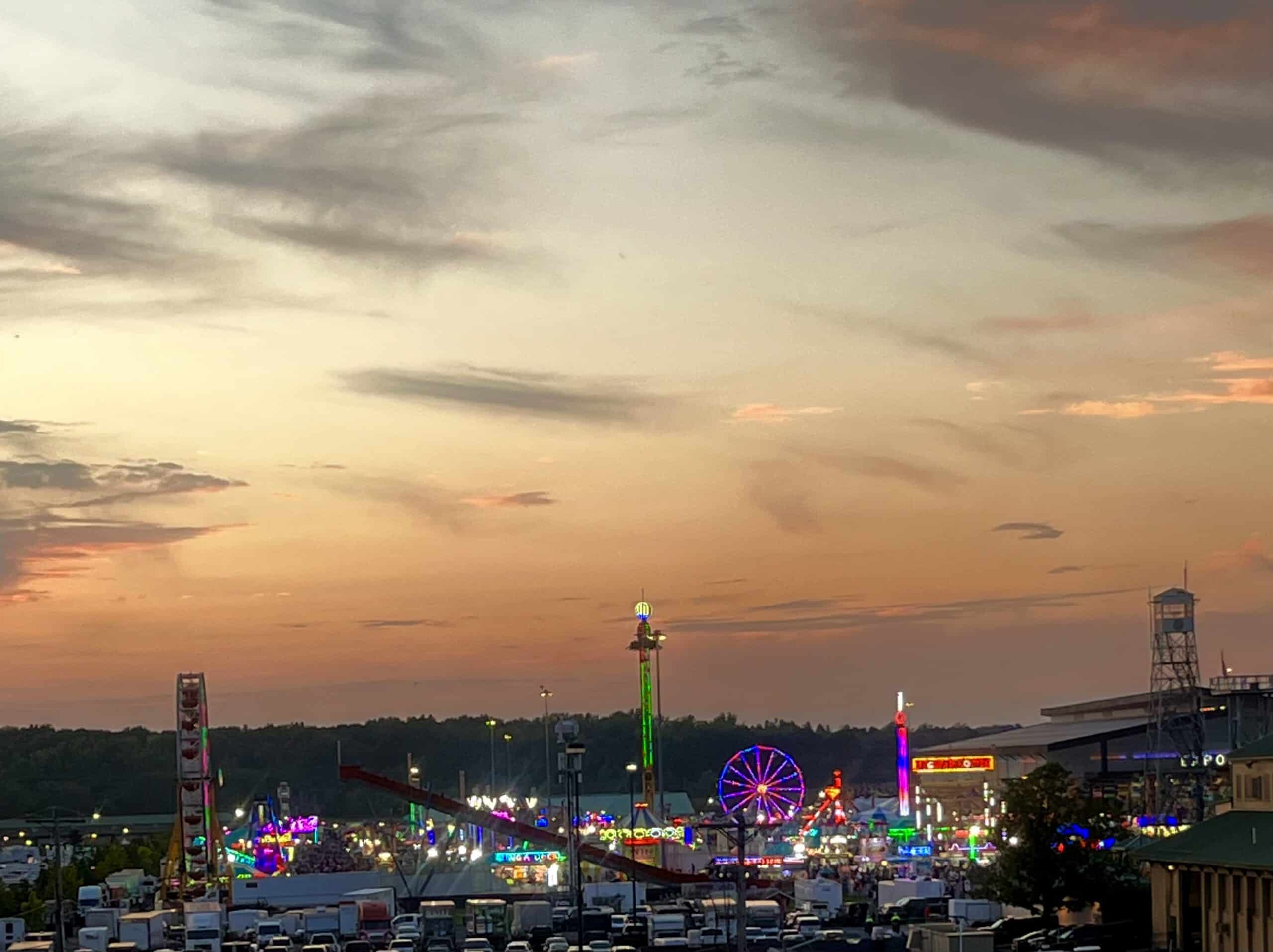 Colorful amusement park rides and Ferris wheel at sunset in Syracuse.