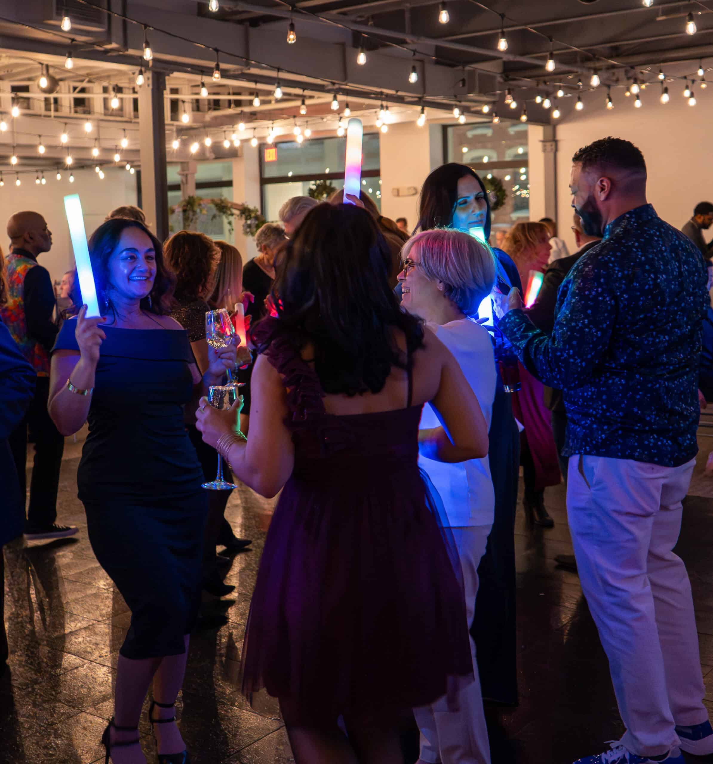 People enjoying a lively night event with glow sticks and drinks at Sky Armory.
