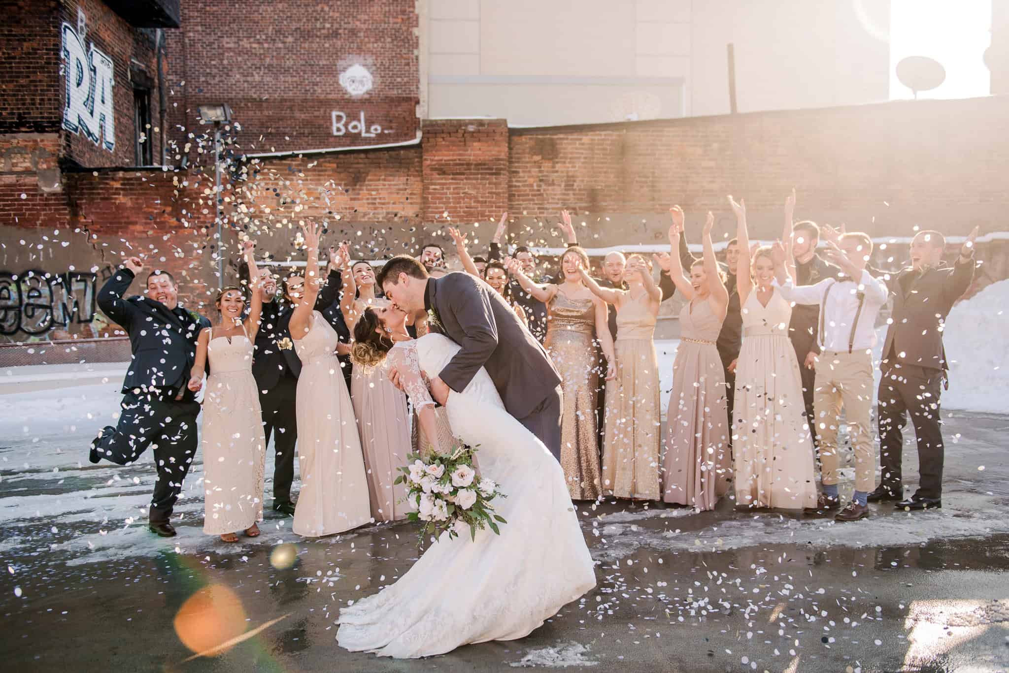 Bride and bridesmaids celebrating outdoors with confetti and joyful expressions.