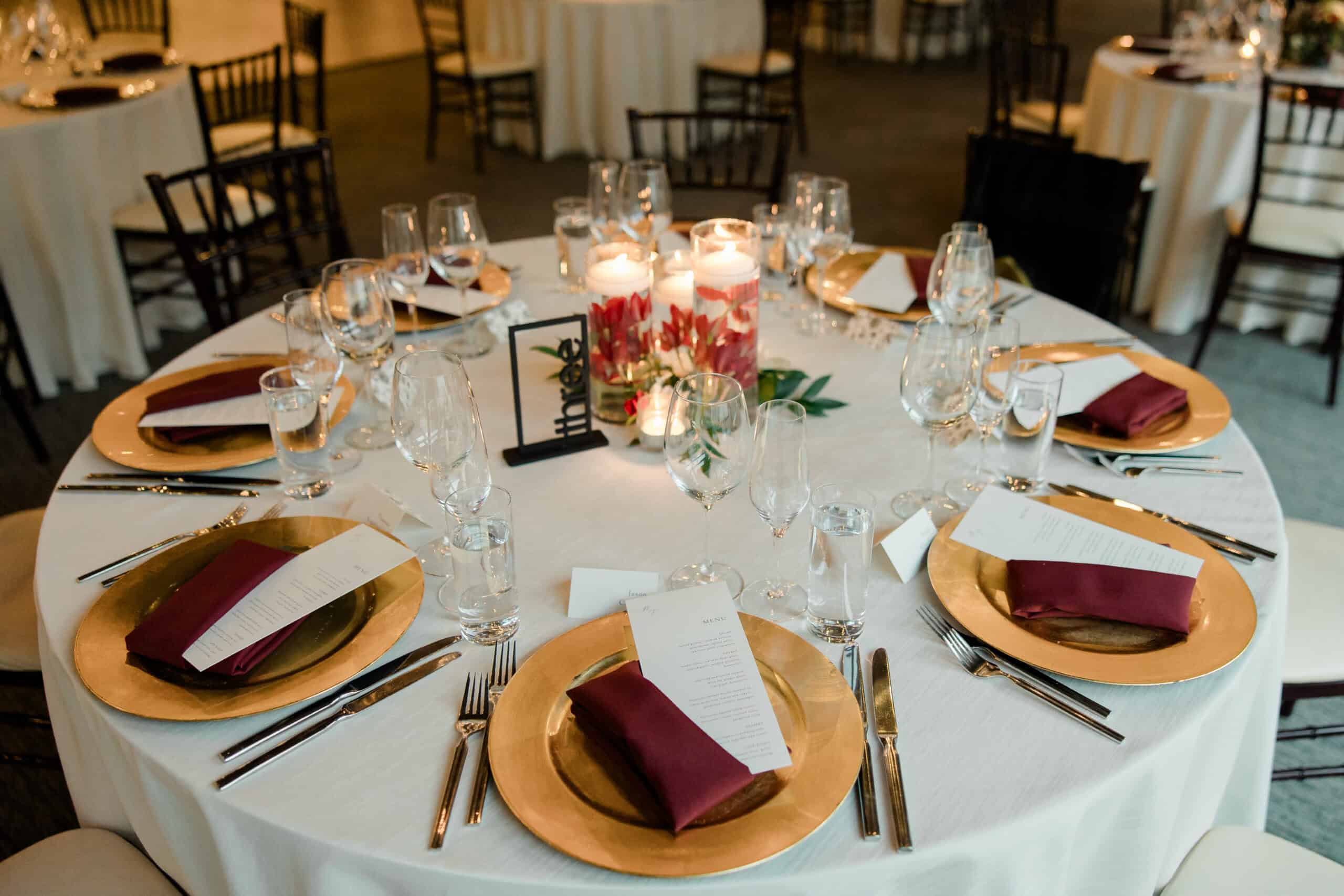 Wedding table setup with red napkins, candles, and floral centerpiece.