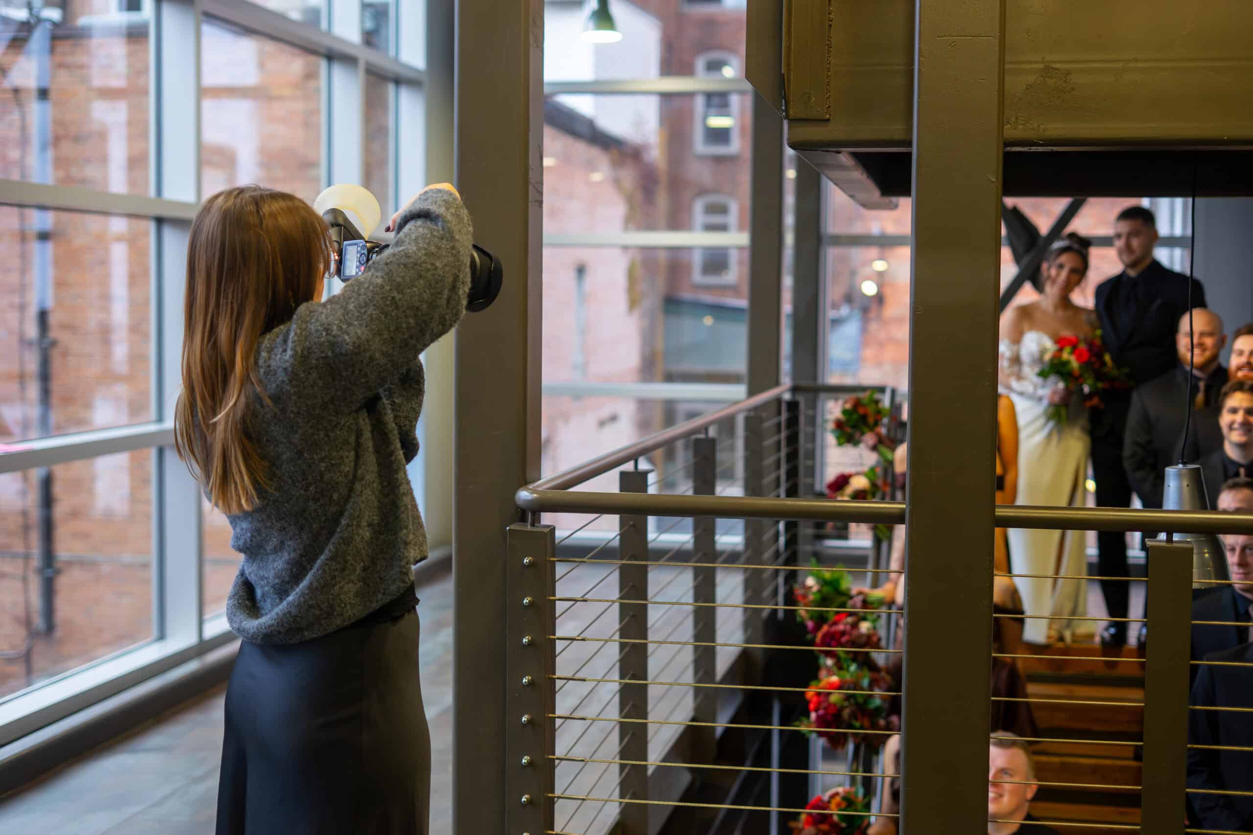 Woman taking photos of wedding guests at Sky Armory venue.