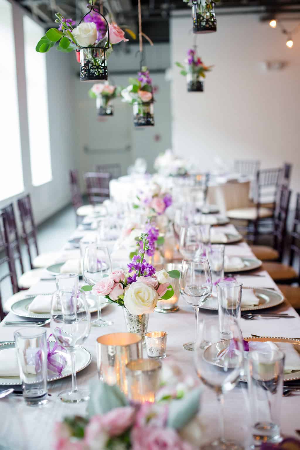 Beautifully decorated wedding reception table with floral centerpieces and hanging lanterns.