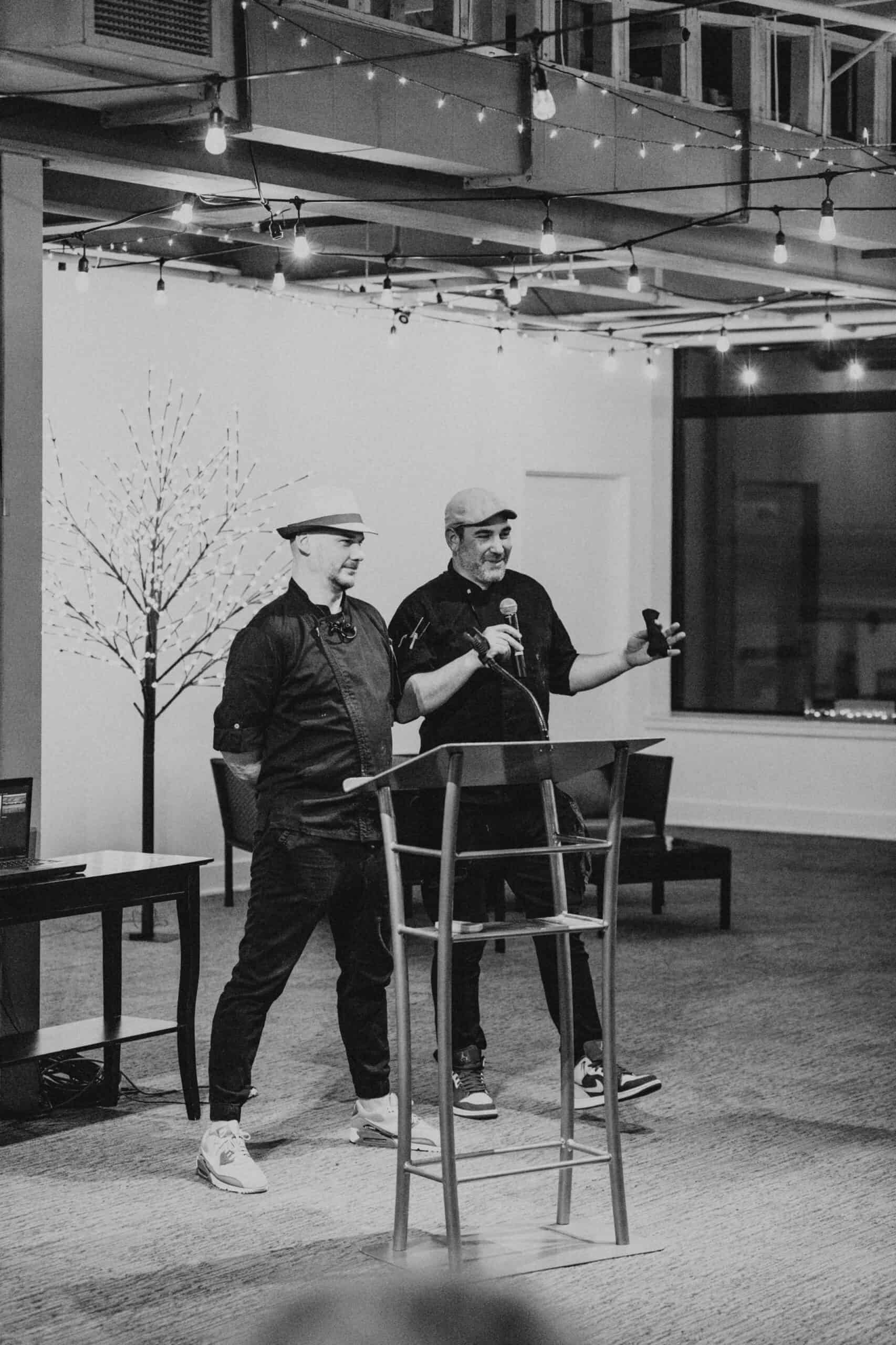 Two men speaking at a podium during the Syracuse Chef Challenge event at SKY Armory.