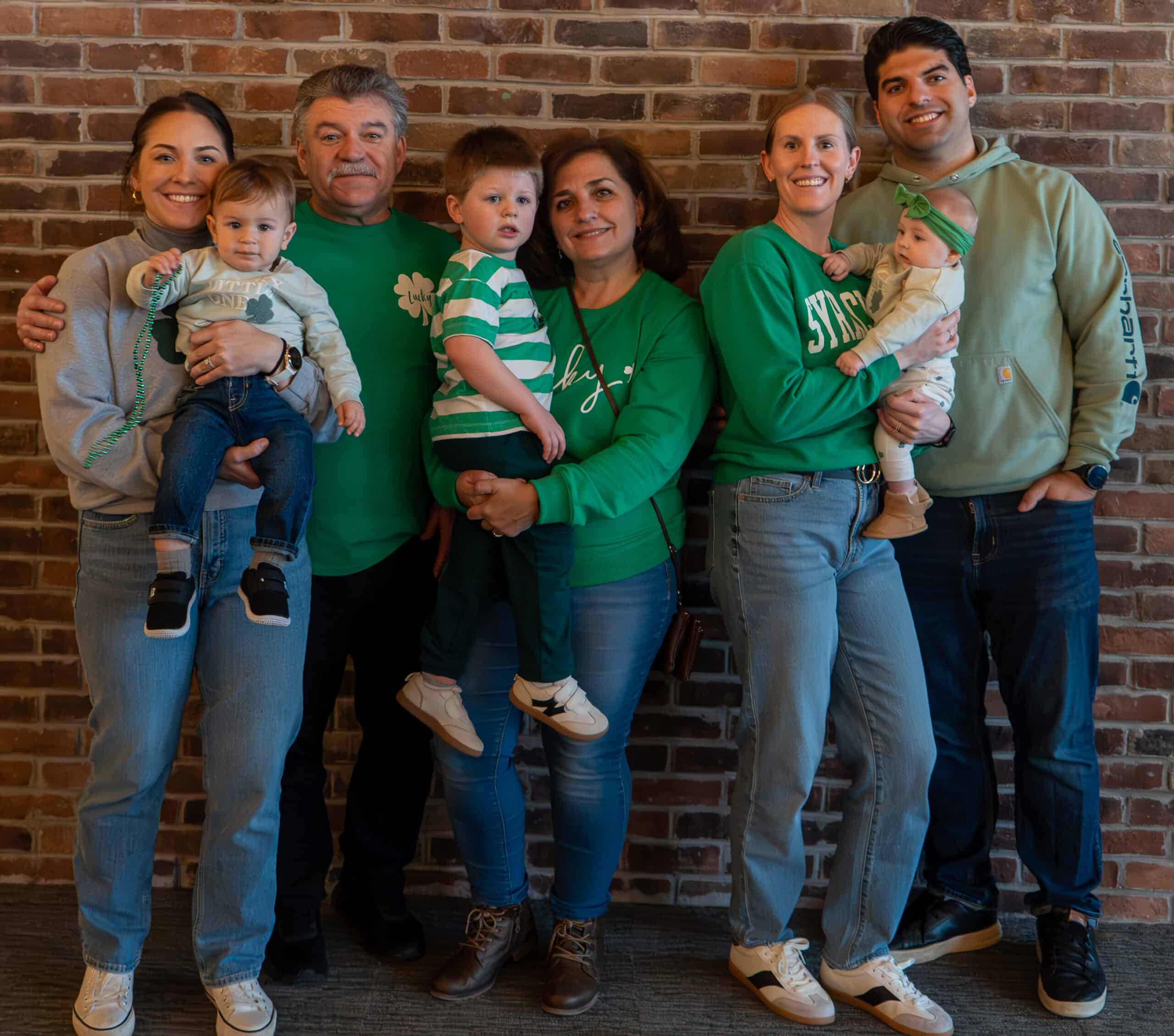 Family group photo at SKY Armory with brick wall background.