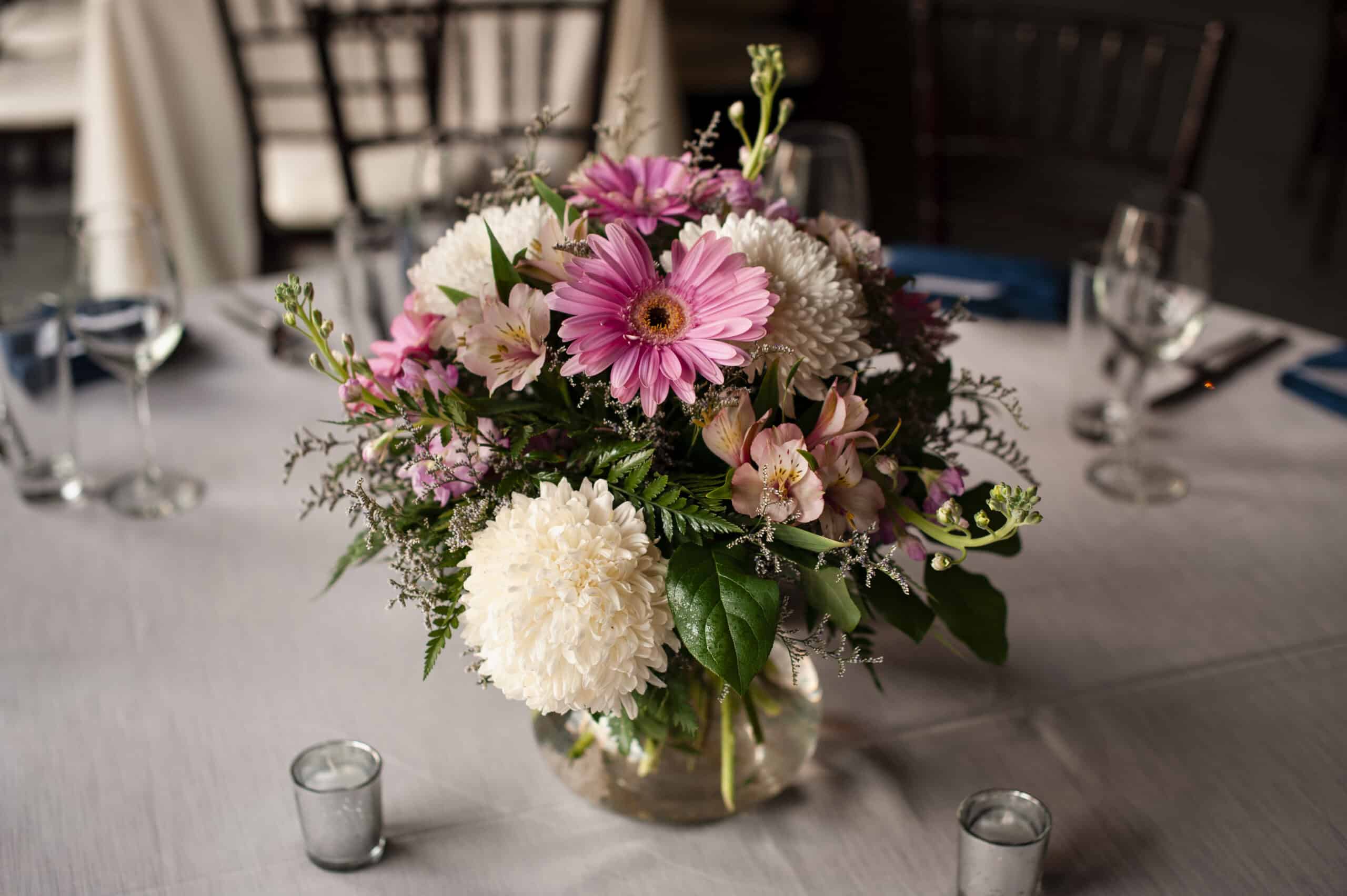 Beautiful pink and white flower arrangement in a glass vase on a dining table.