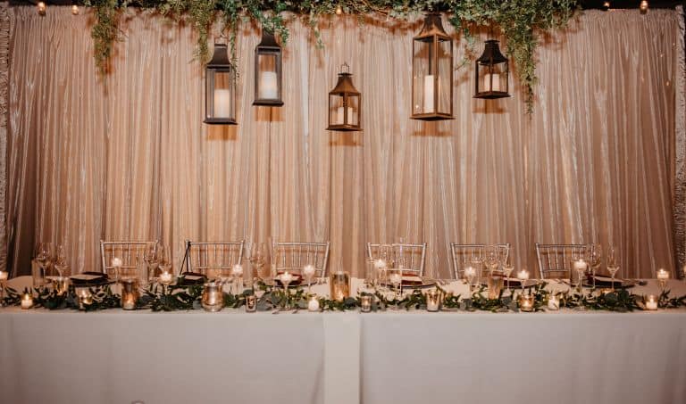 Wedding reception table with lanterns and floral decor at SKY Armory.