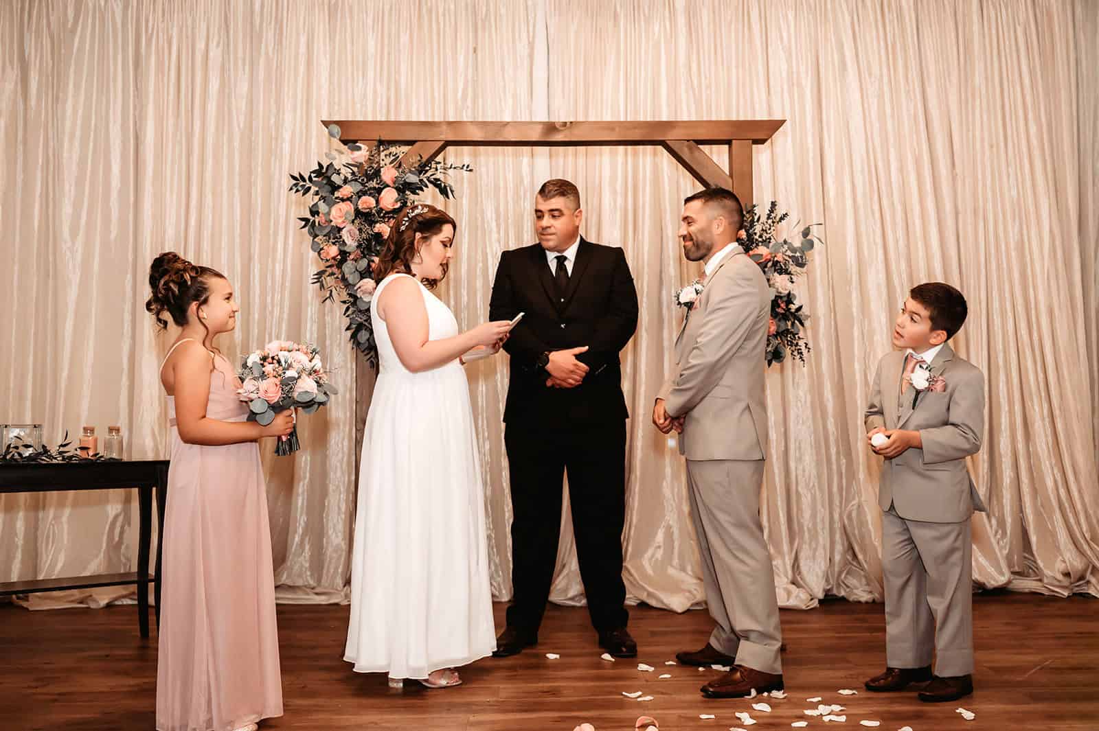 Family and officiant during wedding ceremony with floral backdrop.