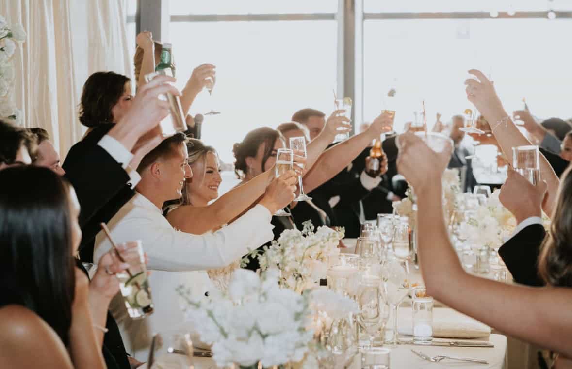 Guests raising glasses in toast at wedding reception.